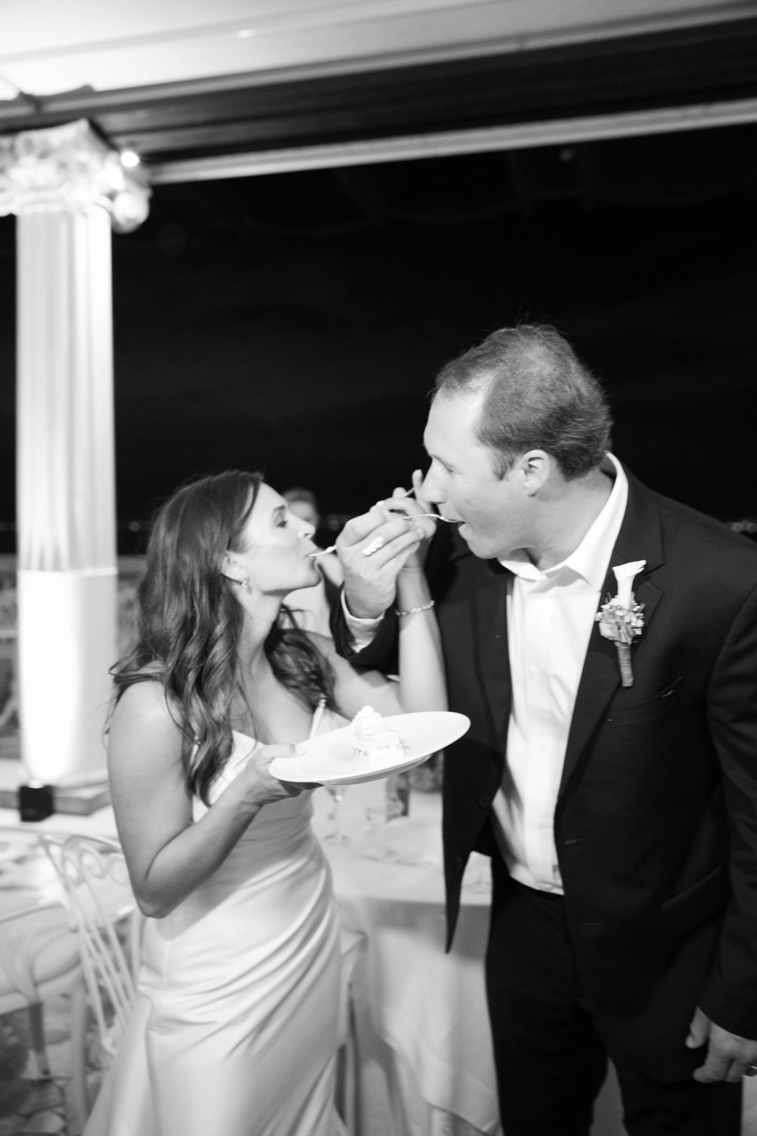 Black and white photo of the bride and groom feeding each other wedding cake
