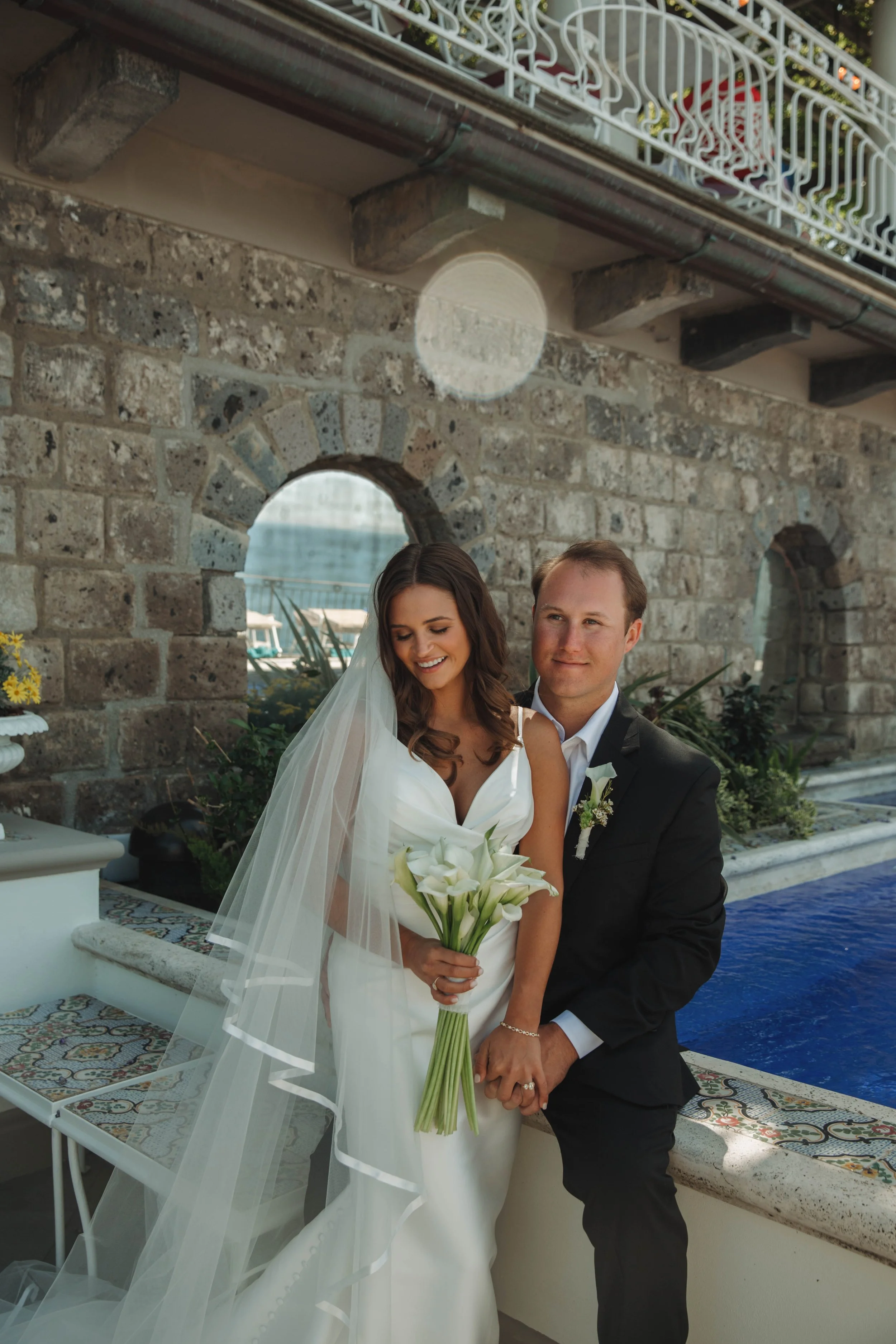Bride and groom holding hands beside the pool at the Bellevue Syrene in Sorrento, Italy