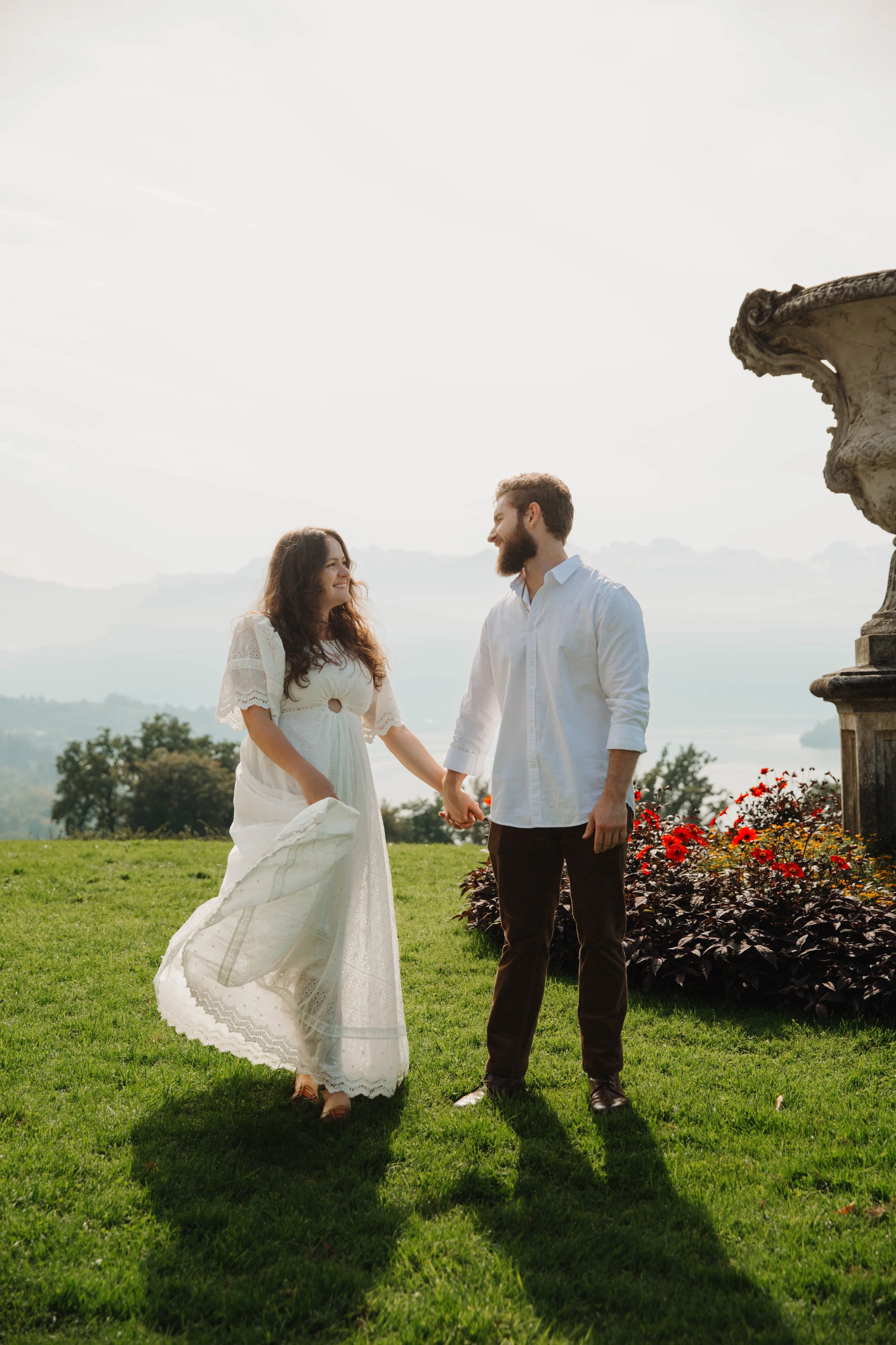 Couple holding hands in a garden overlook above Lucerne with the lake behind them