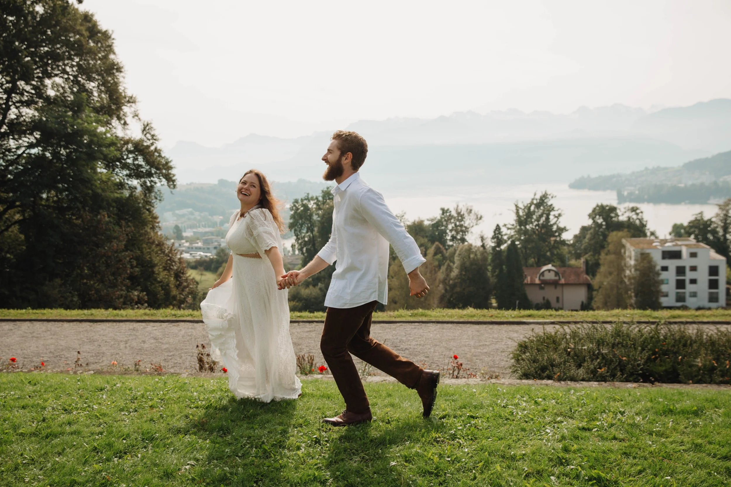 Engaged couple running hand in hand through a garden above Lucerne at golden hour