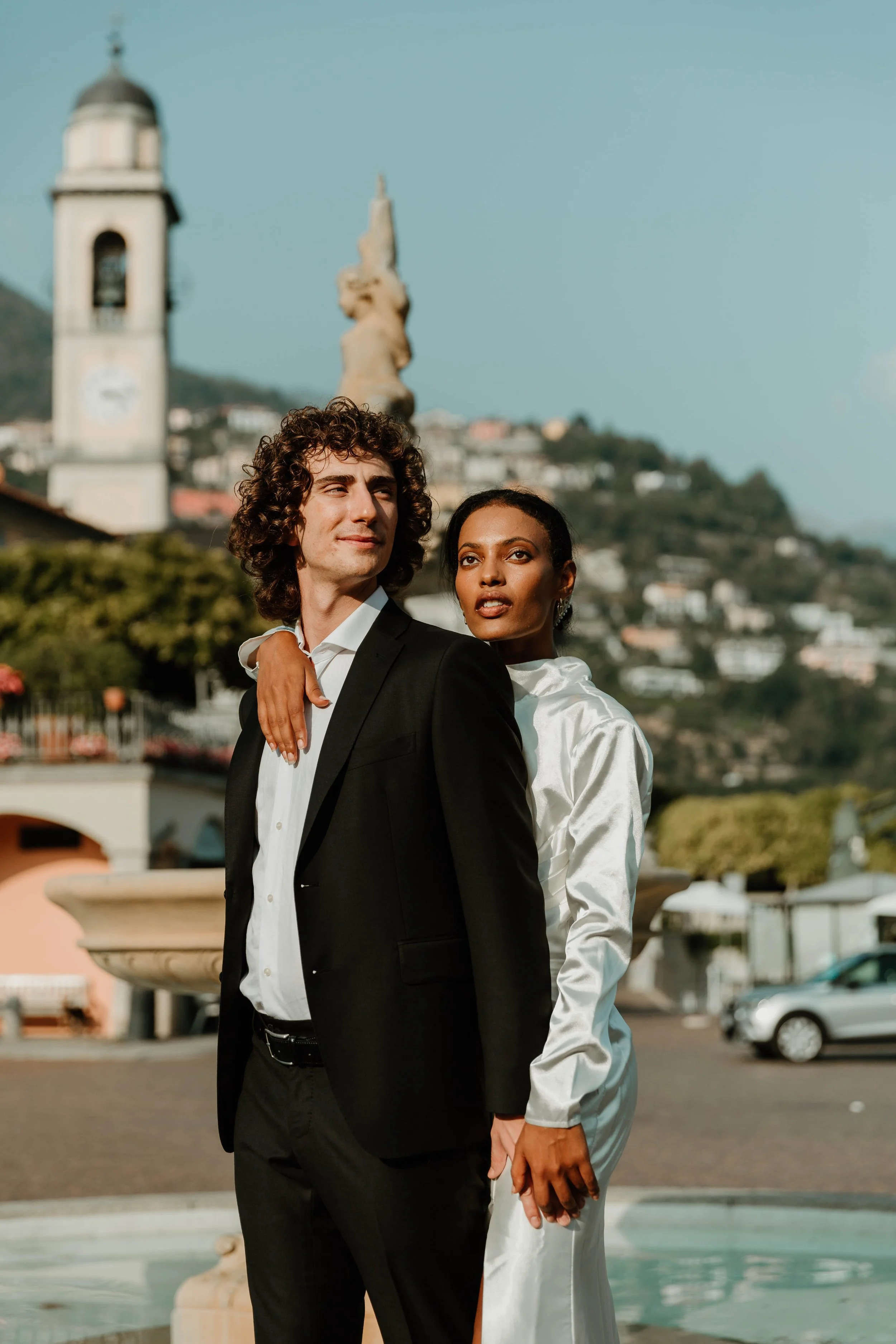 Couple standing in front of the bell tower and fountain in Cernobbio, Italy