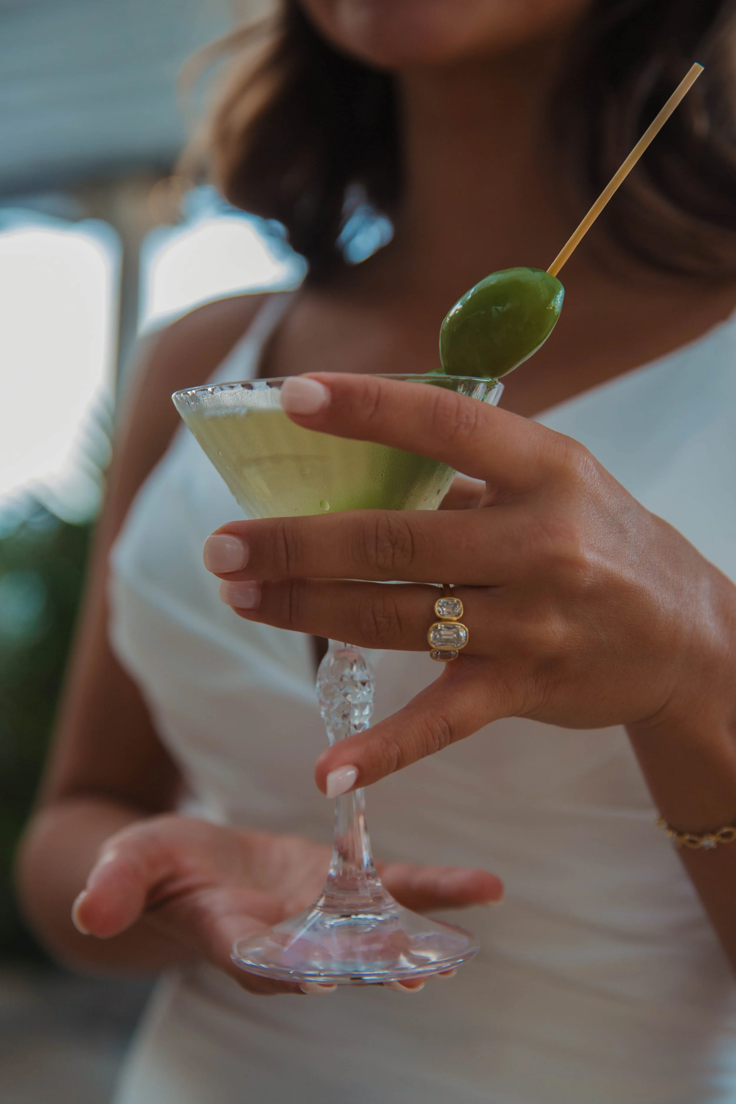 Bride holding a martini with an olive showing her wedding ring at a Sorrento reception