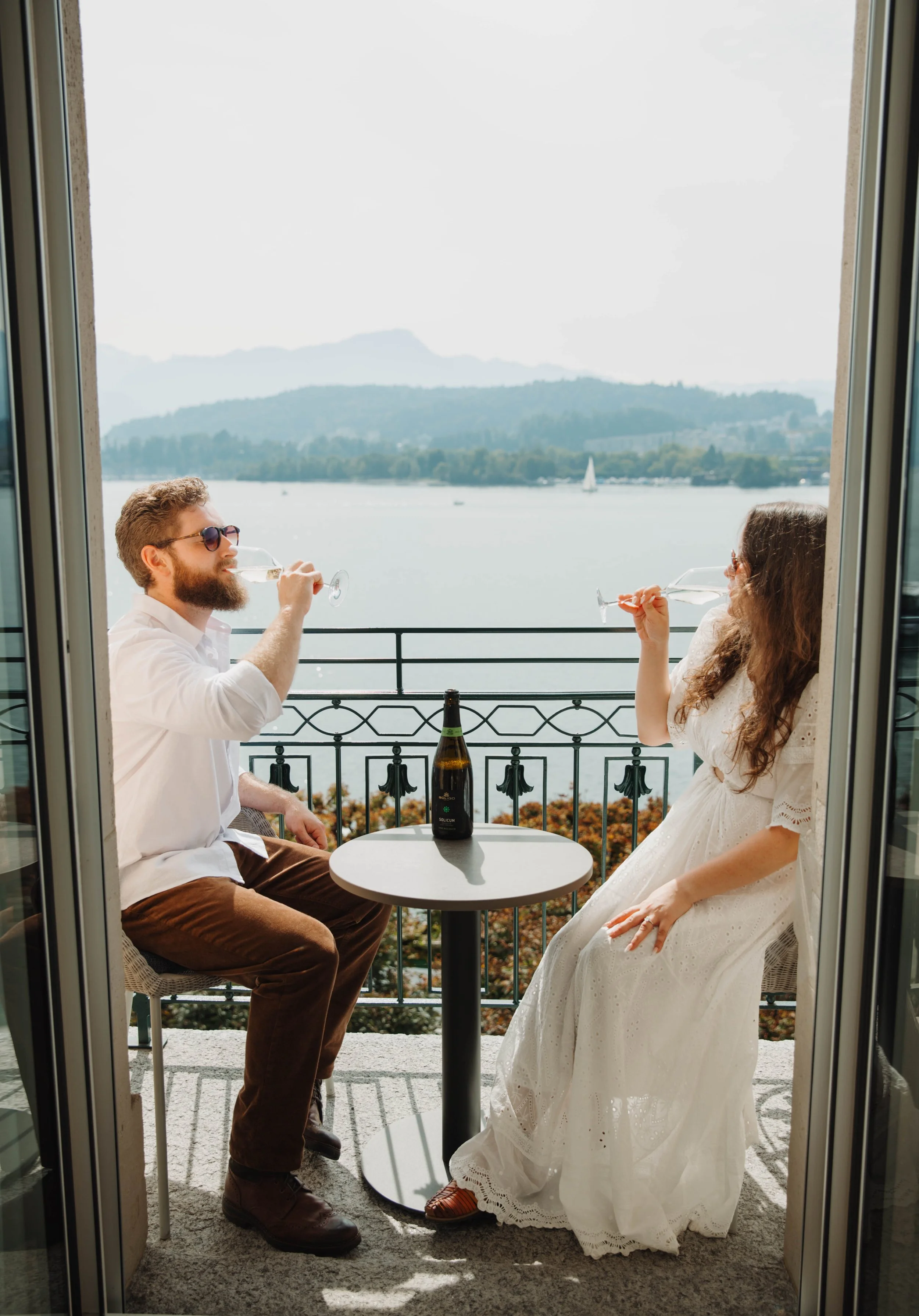 Engaged couple drinking champagne on a balcony overlooking Lake Lucerne, Switzerland