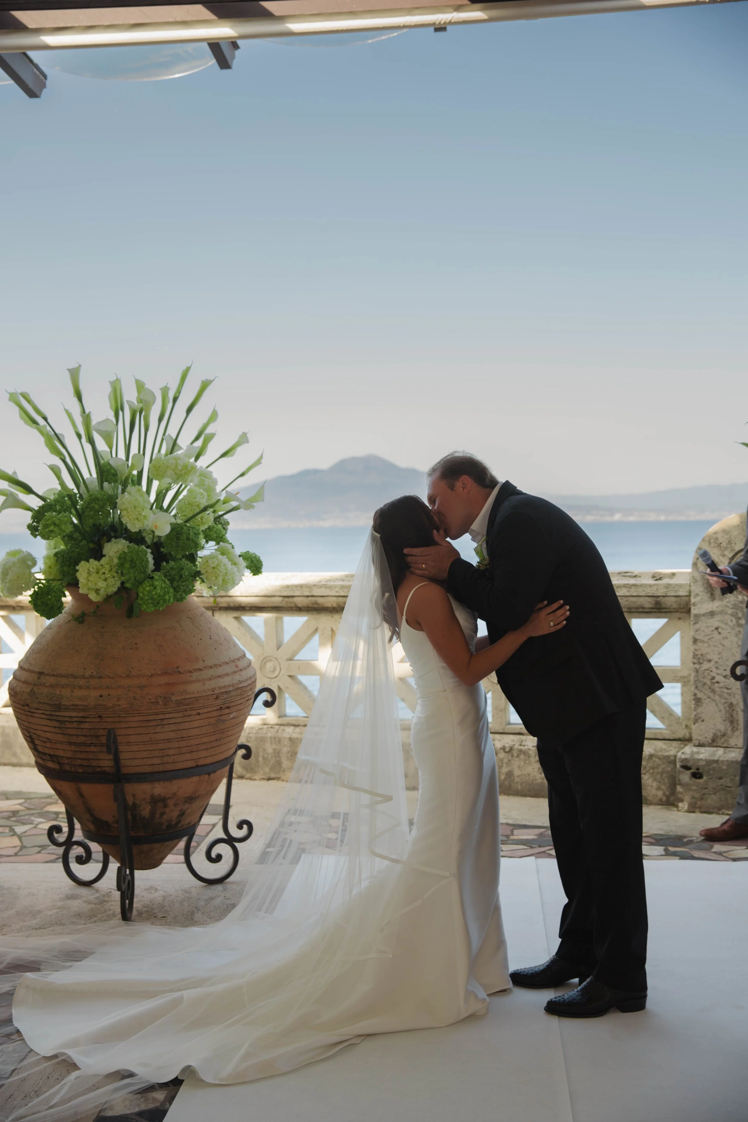 First kiss at a terrace wedding ceremony at the Bellevue Syrene with the Bay of Naples behind