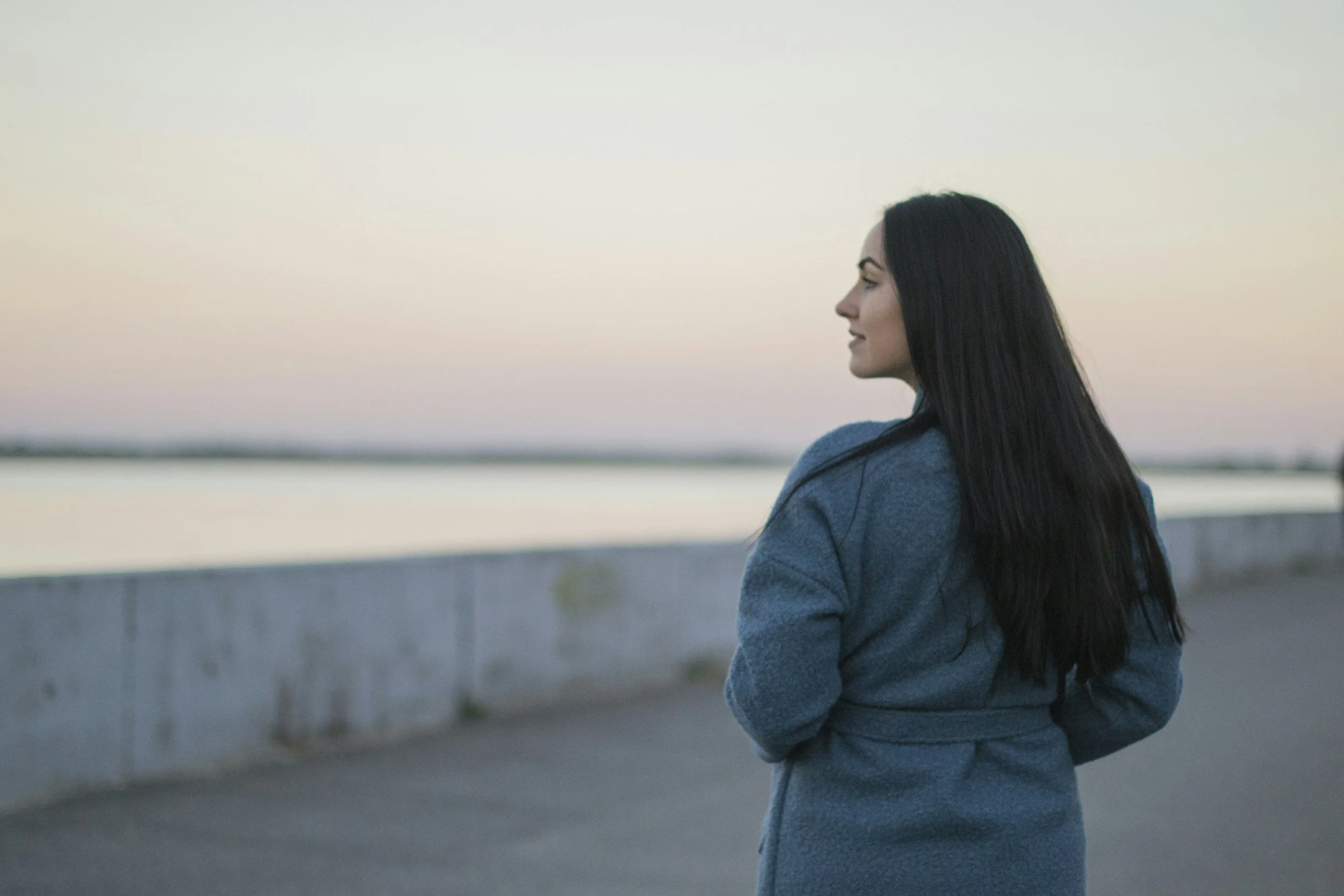 woman with long brown hair looking out over water