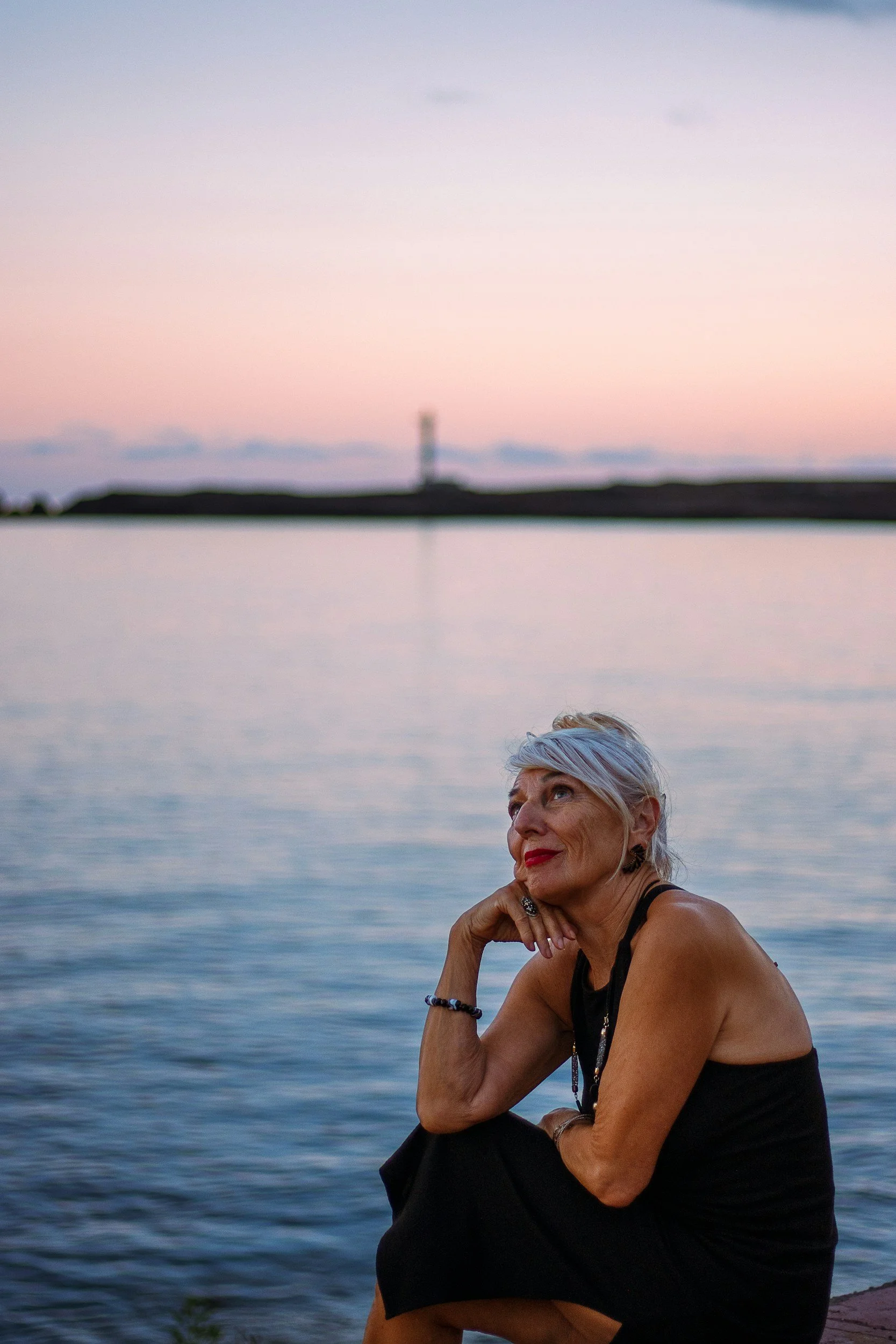 Woman with silver hair sitting in front of lake after anxiety therapy in Baton Rouge