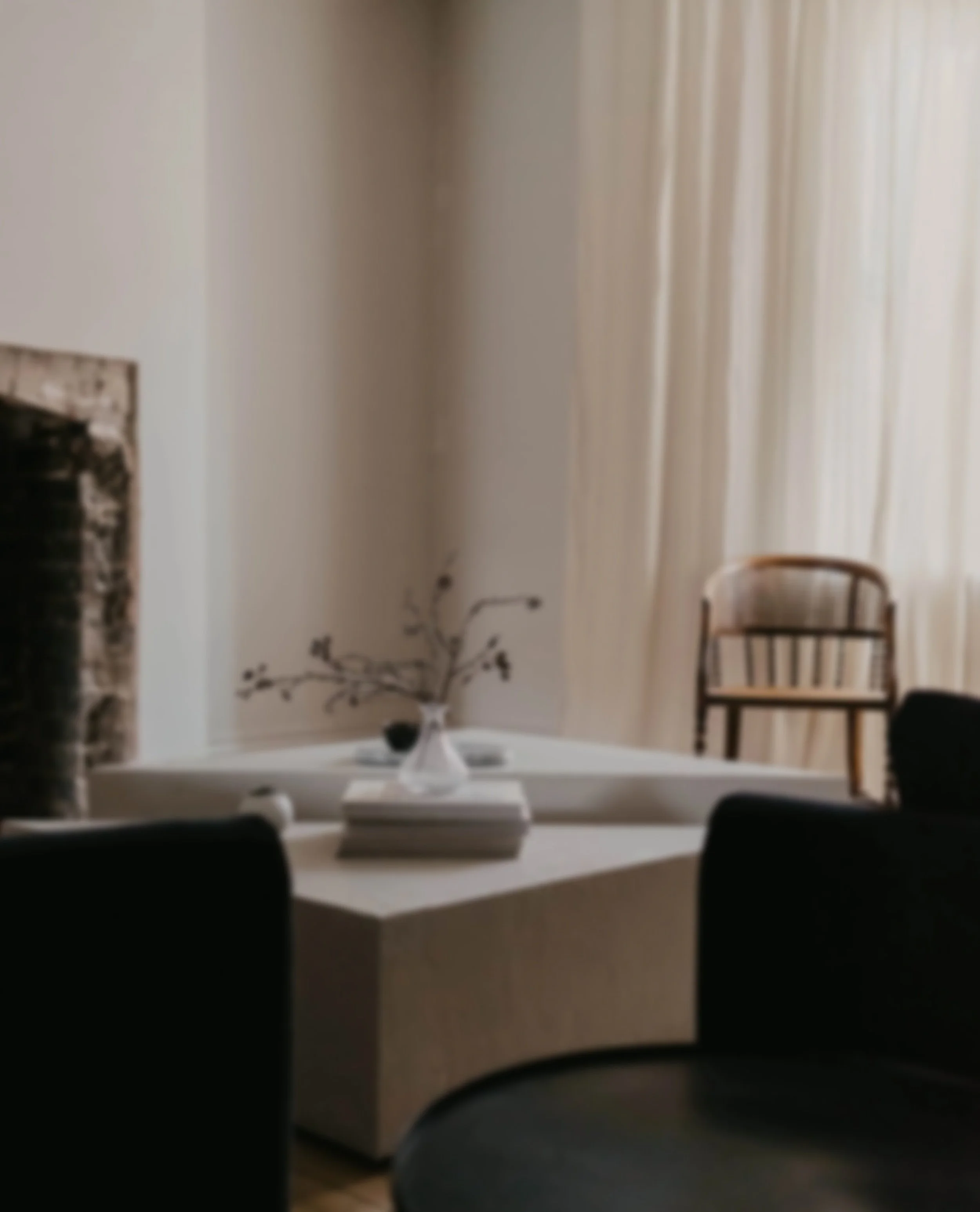 A room for therapy for narcissistic abuse with a white table, a floral centerpiece, a window with white curtains, and black chairs, seen through a doorway with black framing.