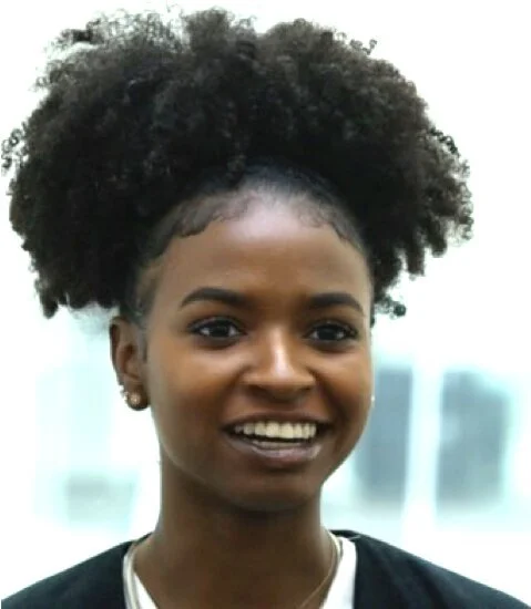 Young African American woman with natural curly hair smiling at the camera.