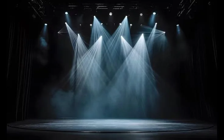 Empty stage with multiple bright blue and white spotlights shining downward.