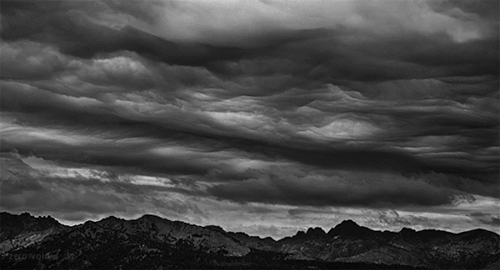 Dark, stormy clouds over mountain landscape in black and white.