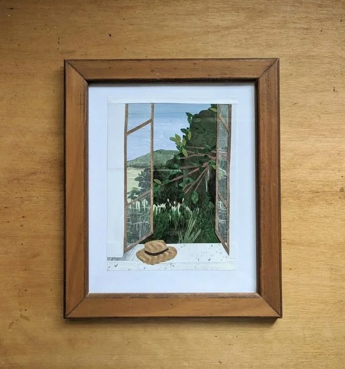A framed illustration of an open window with a view of green trees and hills outside, with a straw hat resting on the windowsill.