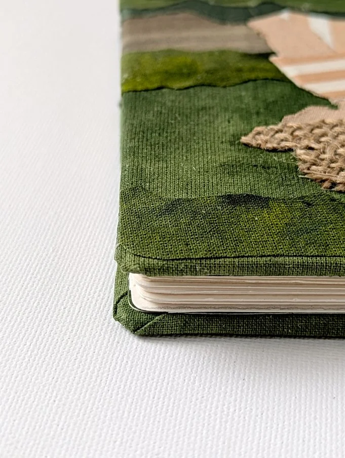 Close-up of a planner or notebook with a green cover resting on a white surface.