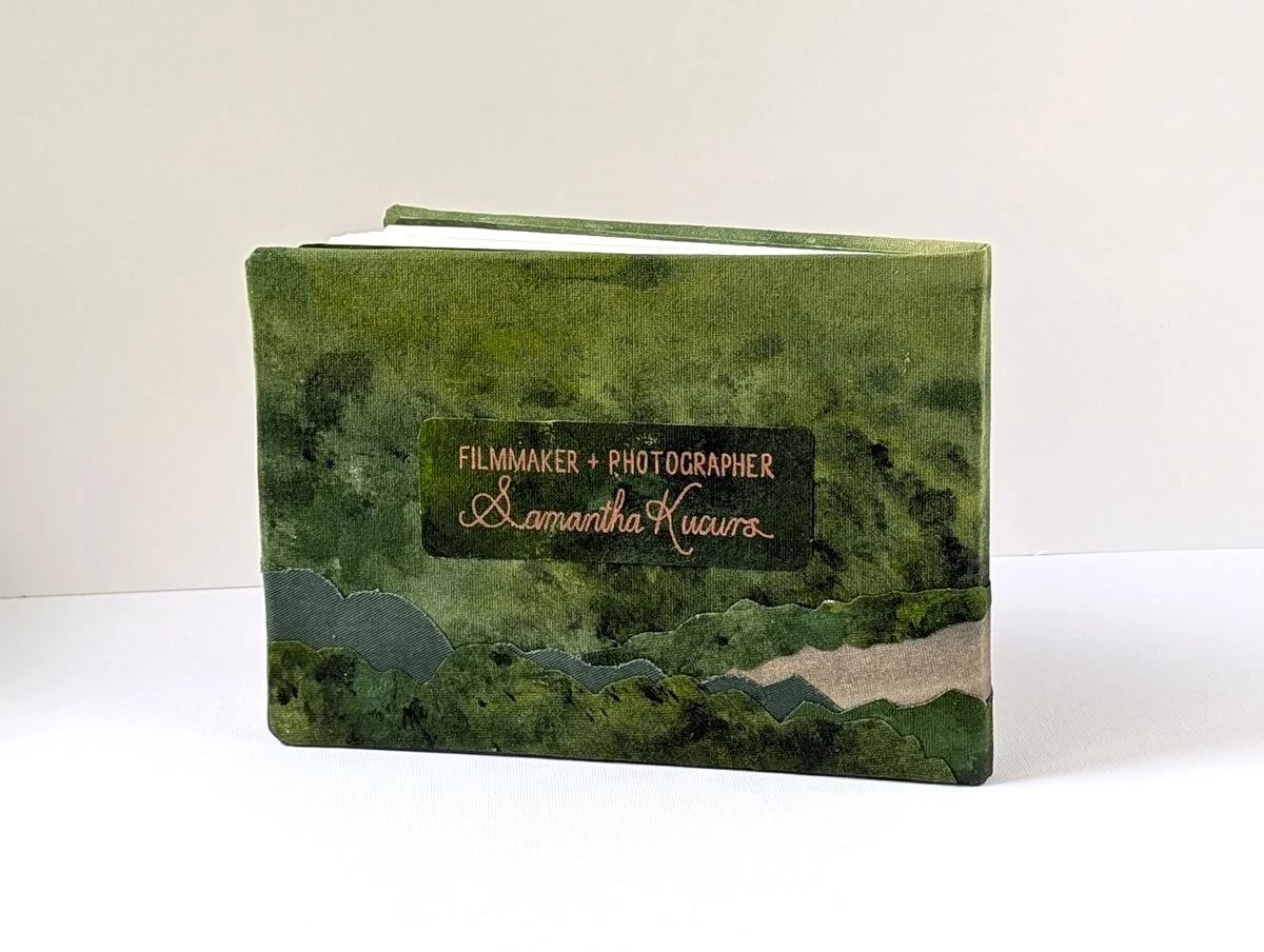A book with a green cover featuring landscape painting and text indicating it is work by filmmaker and photographer Samantha Kucurs.