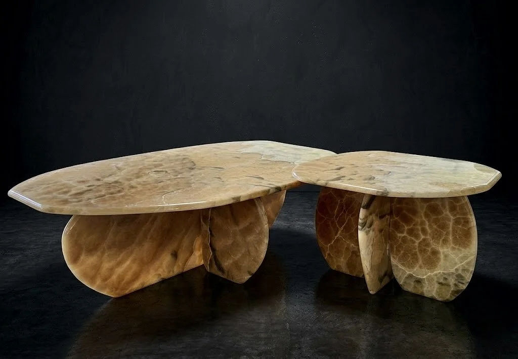 Two abstract, sculptural coffee tables with curved, irregularly shaped stone tops and bases, set against a black background.