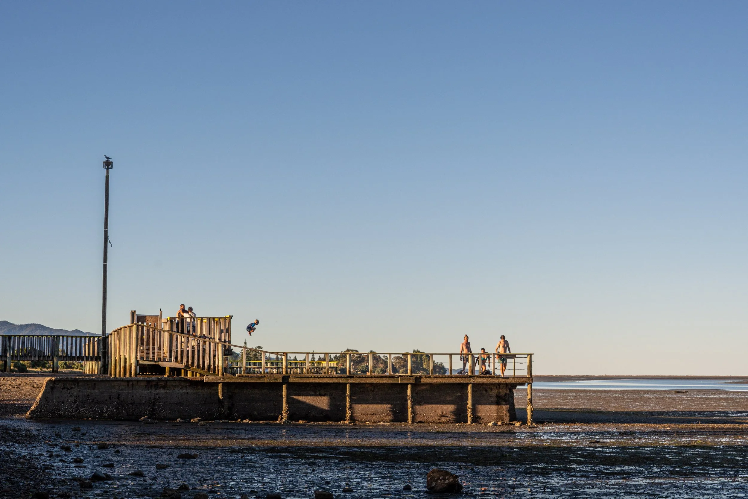 Locals embrace the final hours of daylight, swimming in the Saltwater Baths, overlooking the Tasman Bay.