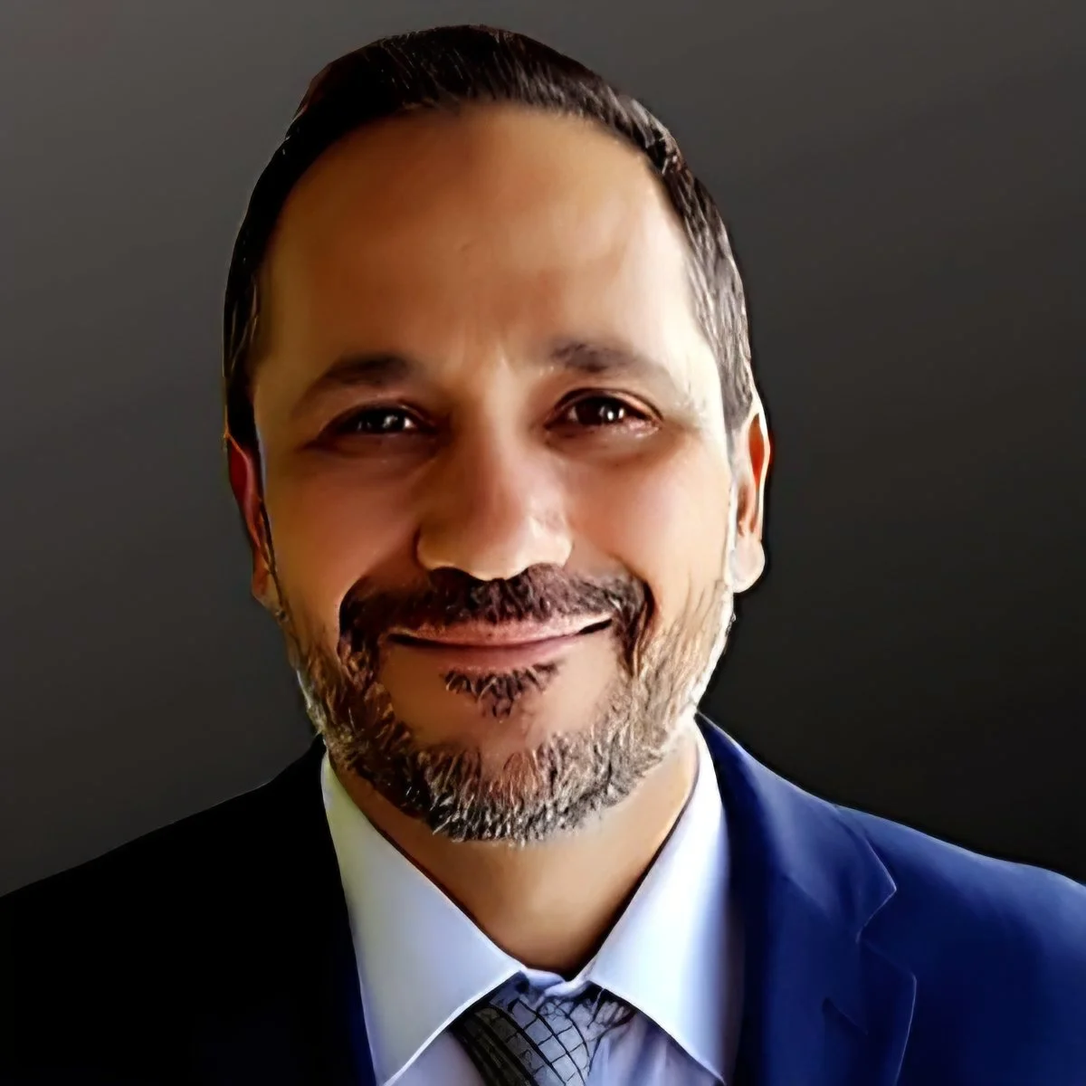 Black and white headshot of a middle-aged man with short hair, beard, smiling, wearing a suit and tie.