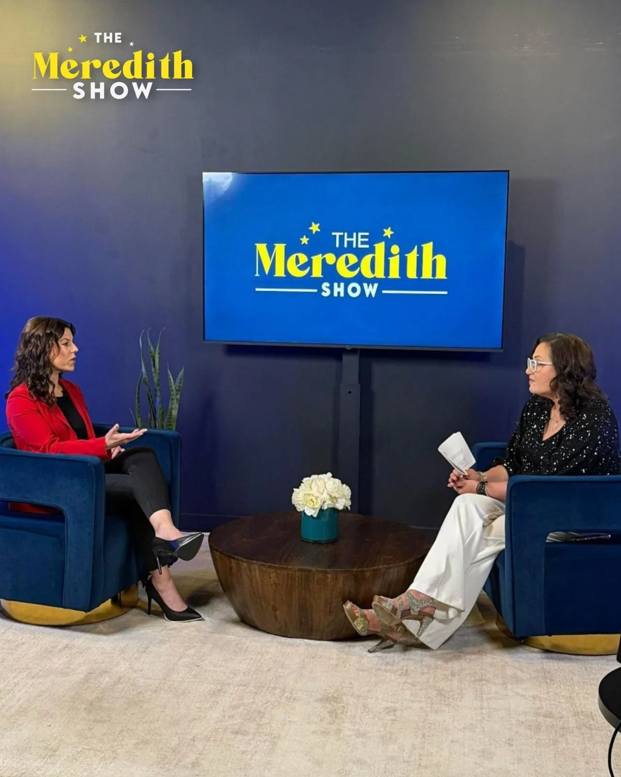 Two women have a conversation on a talk show set with a large TV screen displaying "The Meredith Show" logo in the background.