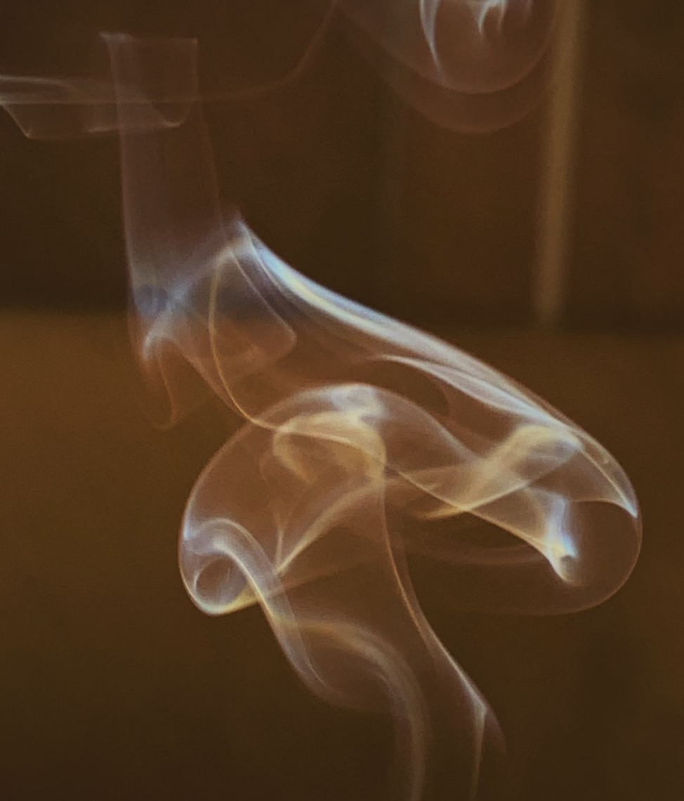 Close-up view of swirling, delicate smoke trails against a dark background.