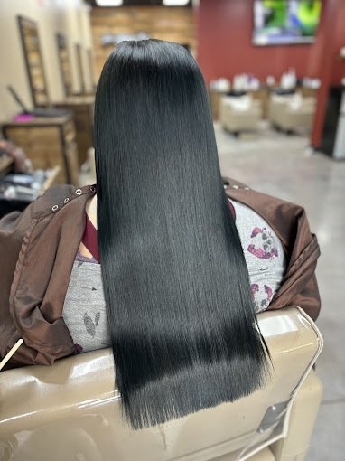 Person with long, straight, shiny black hair sitting in a salon chair