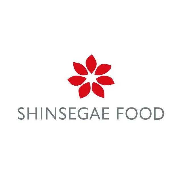 Logo of Shinsegae Food with a red flower-like symbol above the company name in gray text.