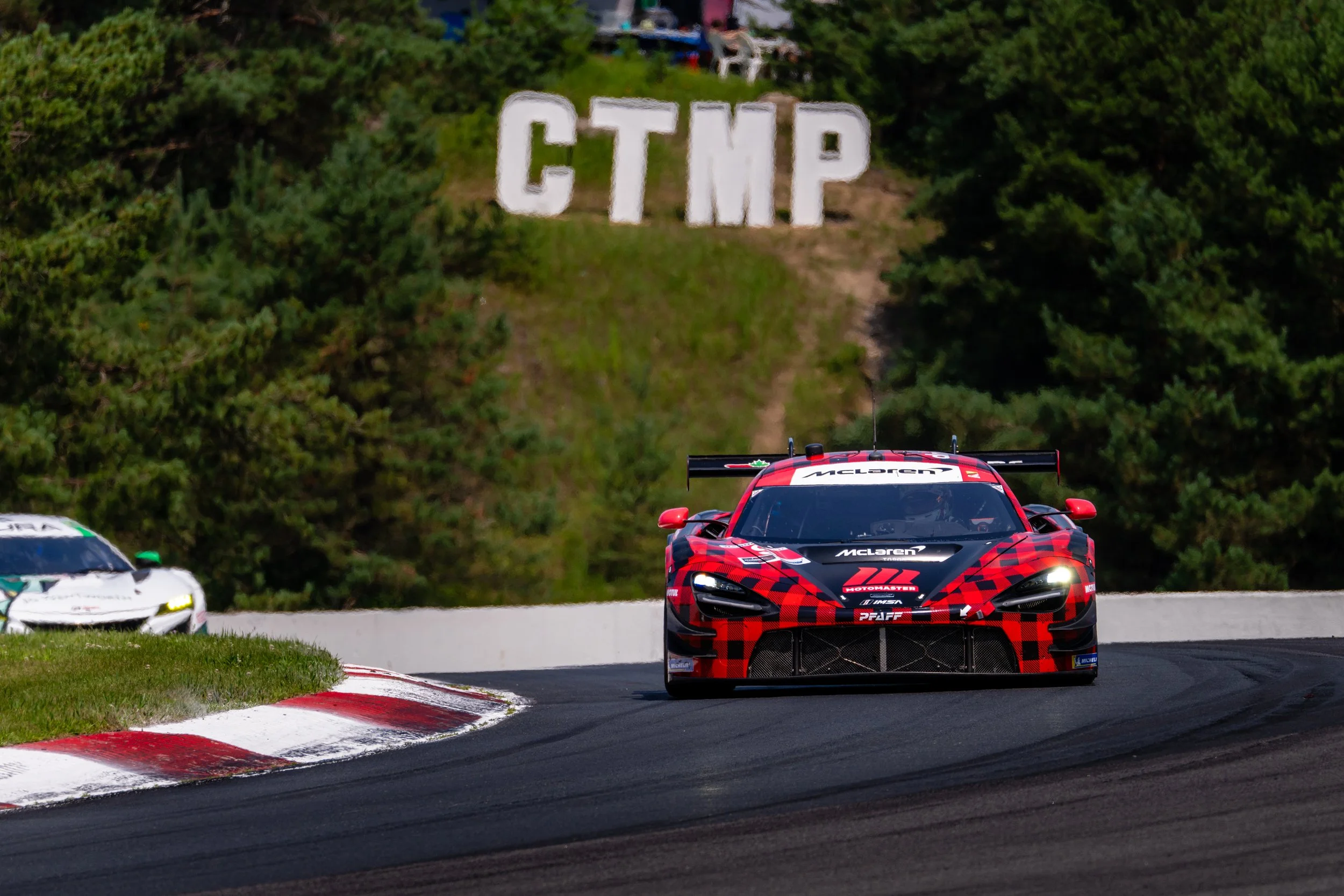 Race cars on track at CTMP, with a Pfaff McLaren racing car in front and a white race car behind.