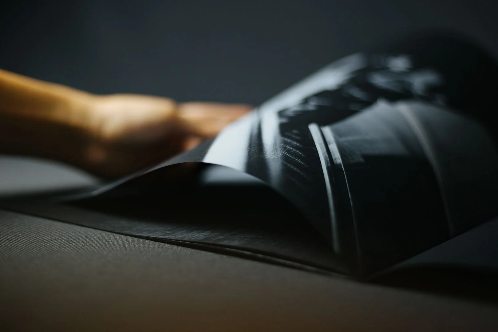 Close-up of a black rotary telephone with a wooden handle, photographed on a dark surface.