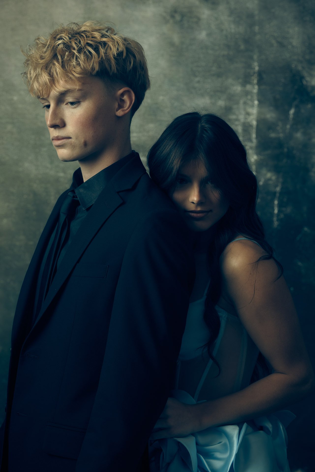 Two high school seniors photographed together in a moody, painterly studio portrait