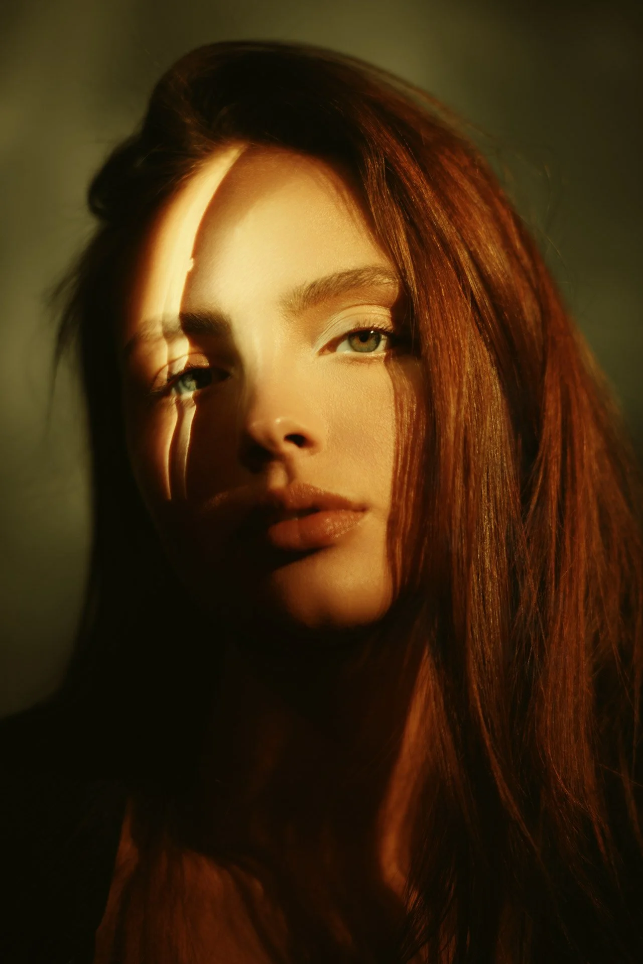 Senior portrait lit with warm amber light raking across the face for a cinematic look
