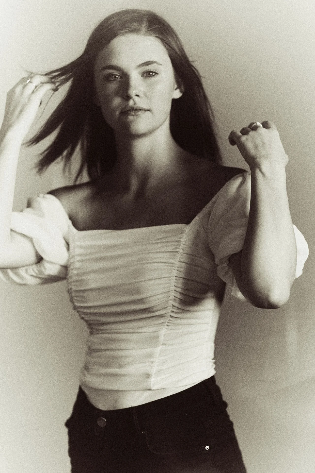 Black and white senior portrait with hair caught mid-motion against a bright studio background