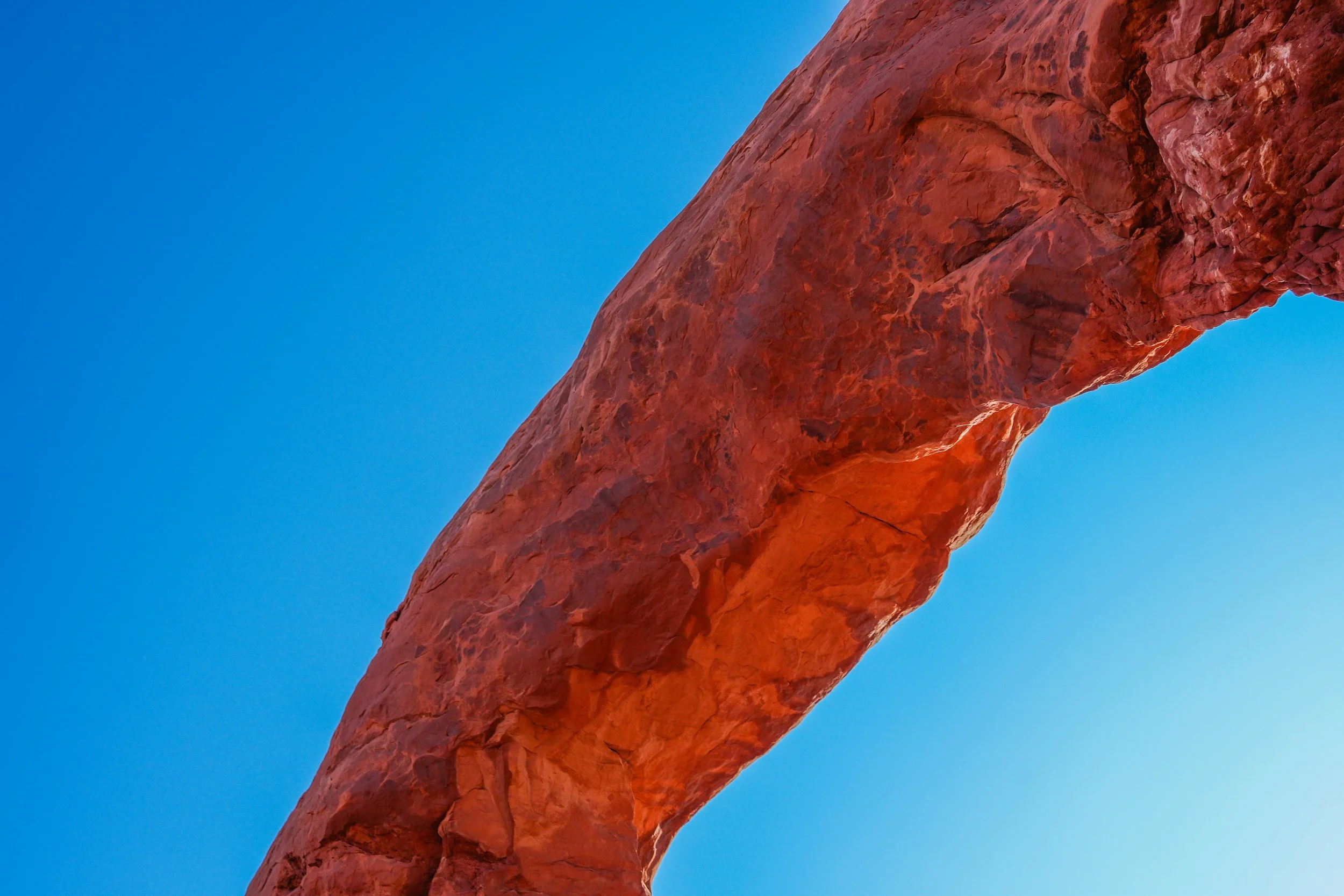 Close-up of a red rock formation with a clear blue sky in the background.