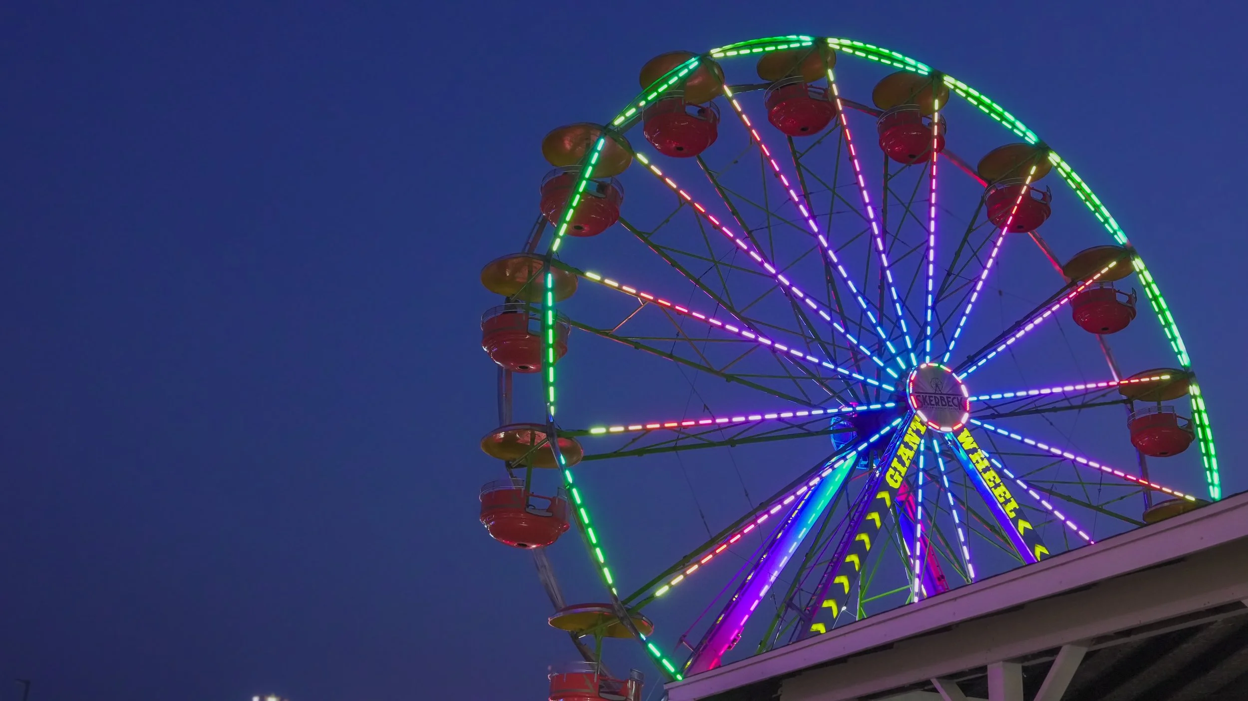 Colorful illuminated Ferris wheel at night sky.