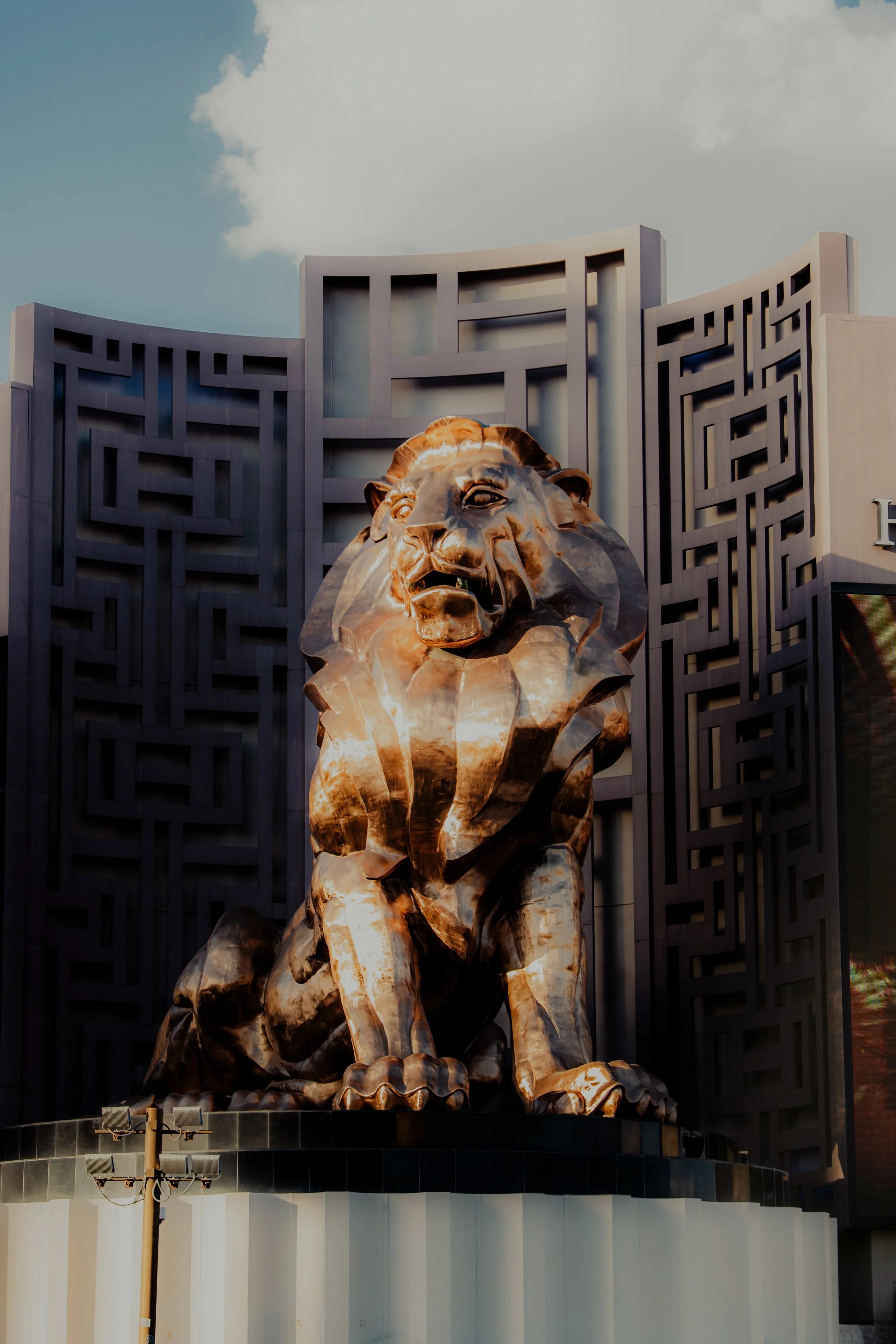 A large, golden lion statue in front of a modern building with geometric patterns in the background.