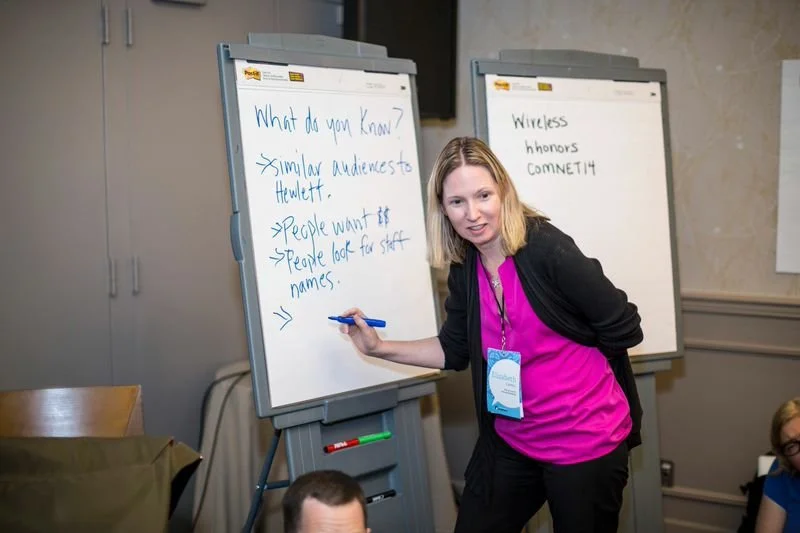 A woman writing on a whiteboard.