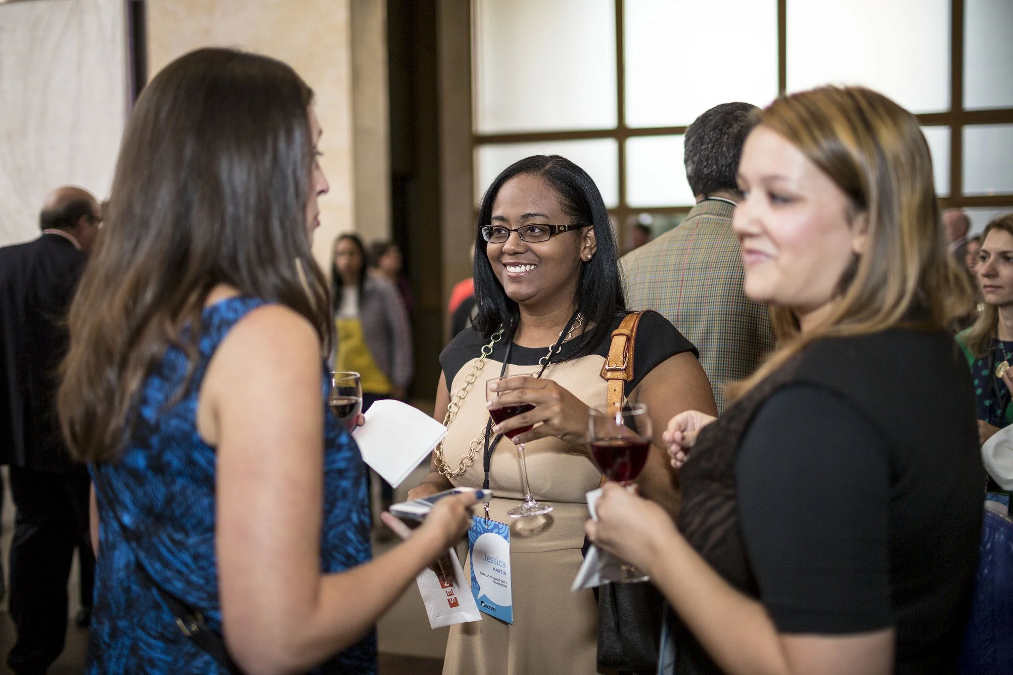 Three woman chatting together with wine glasses in their hands.