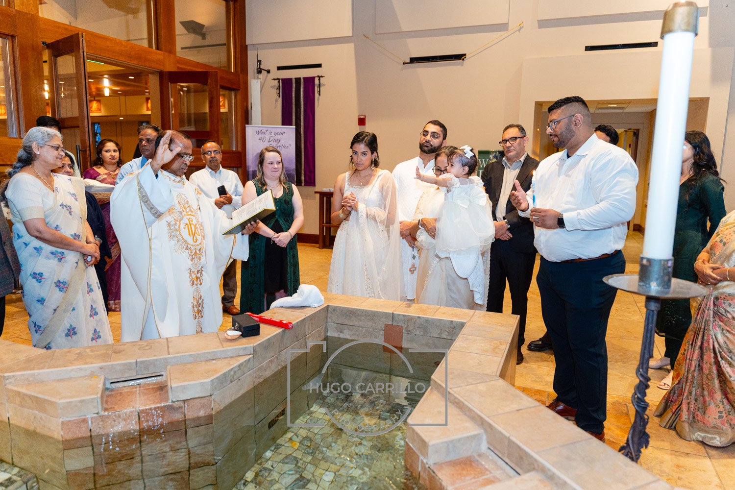 Indian wedding ceremony with priest conducting rituals by a small water fountain, surrounded by family and friends in formal and traditional attire.