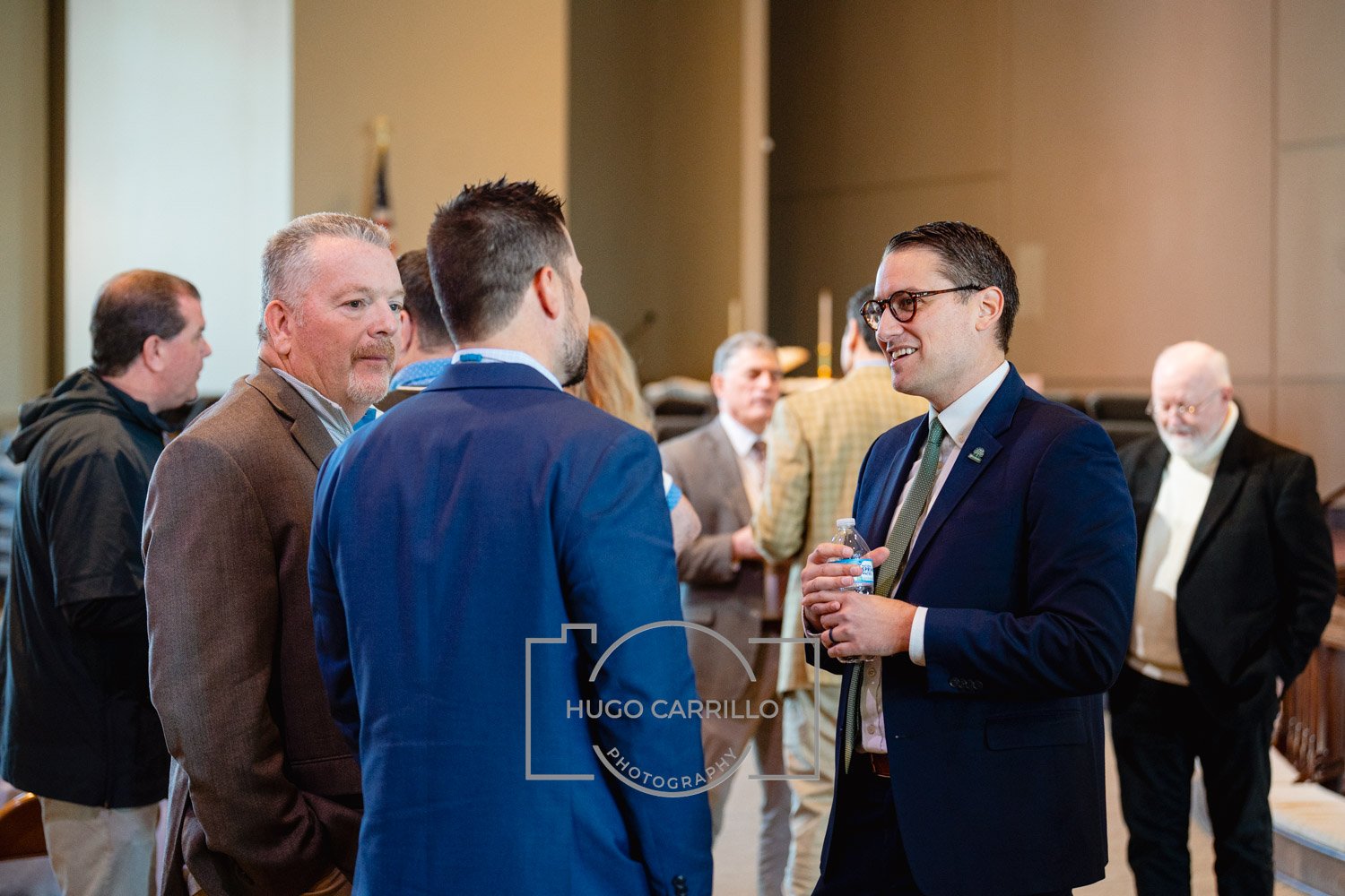 Group of men in formal and semi-formal attire engaged in conversation at an indoor professional event.