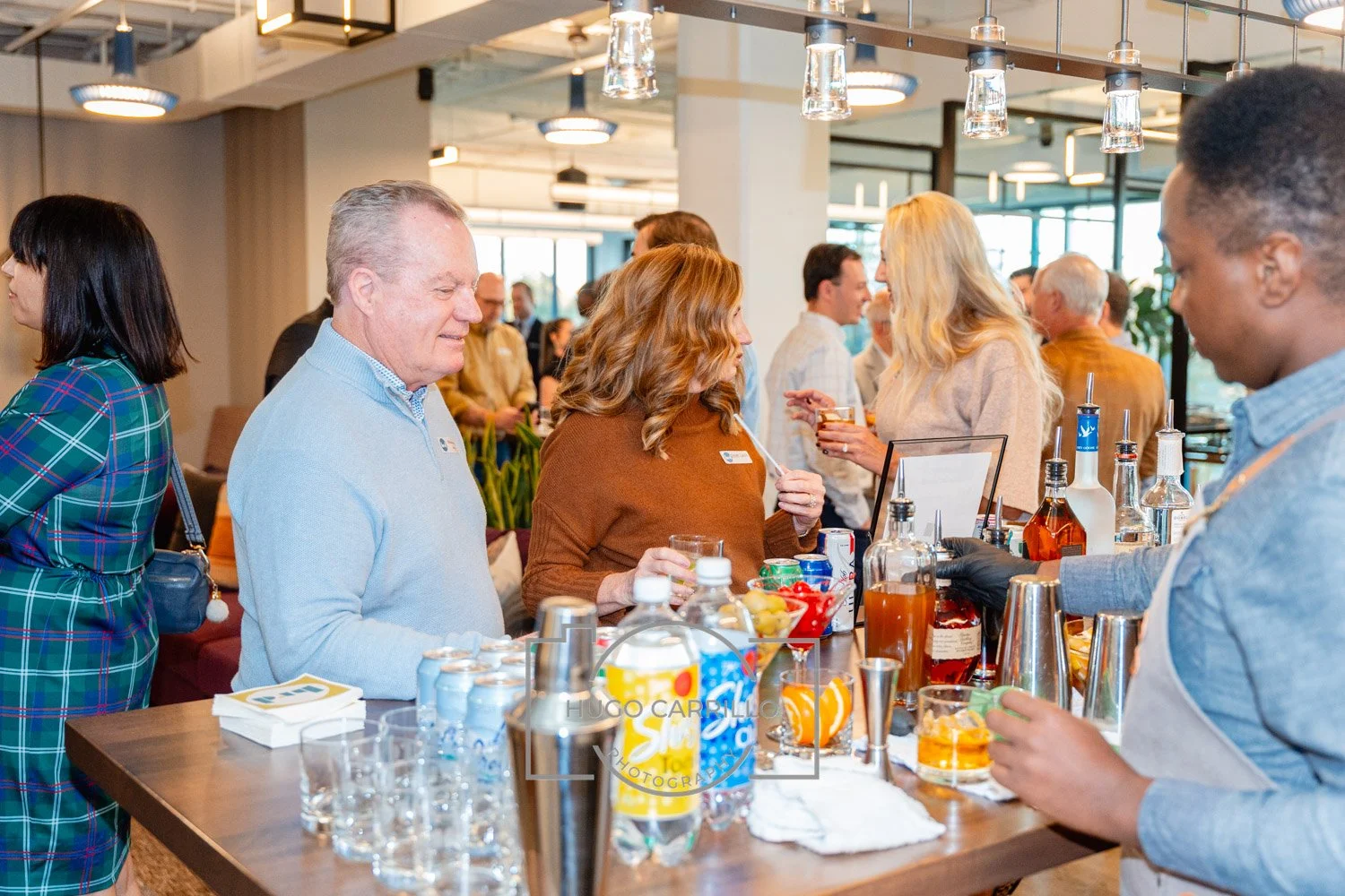 People socializing at a bar with drinks and snacks in a modern indoor setting.