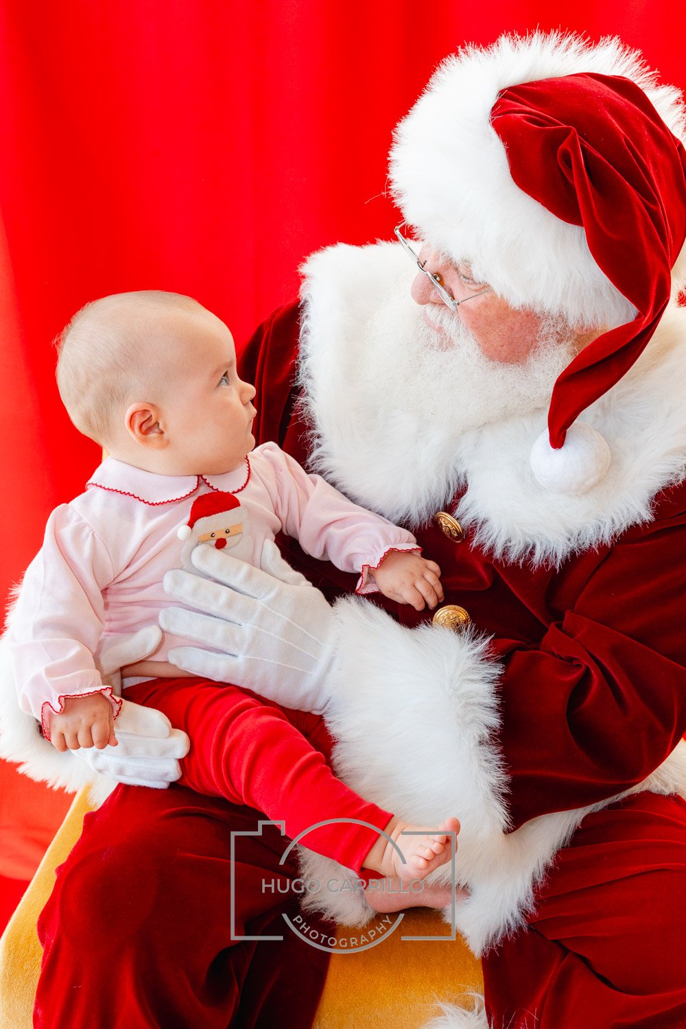 A young child sitting on Santa Claus's lap during a Christmas event.