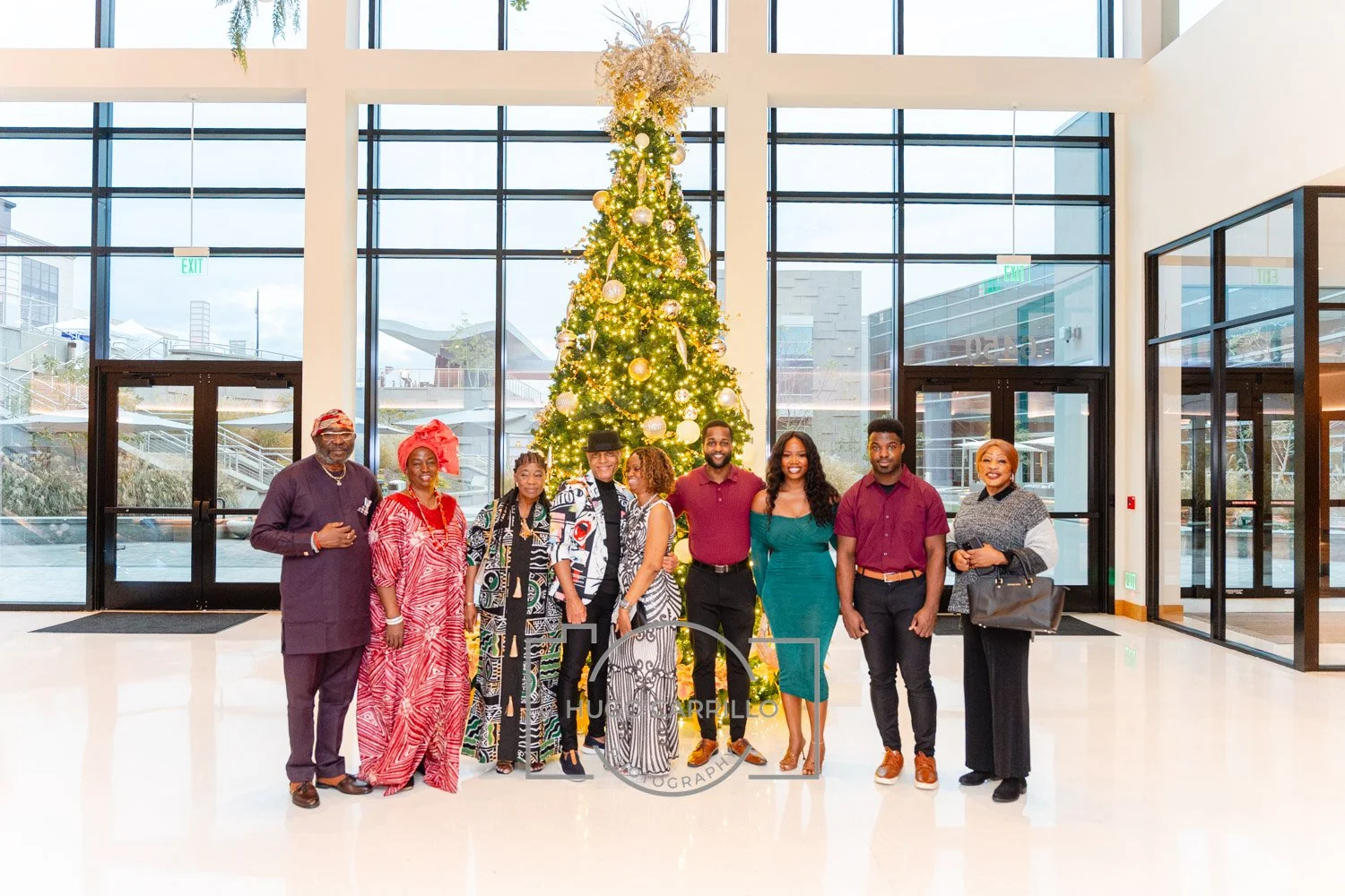 A group of people standing in front of a decorated Christmas tree inside a modern building with large glass windows.