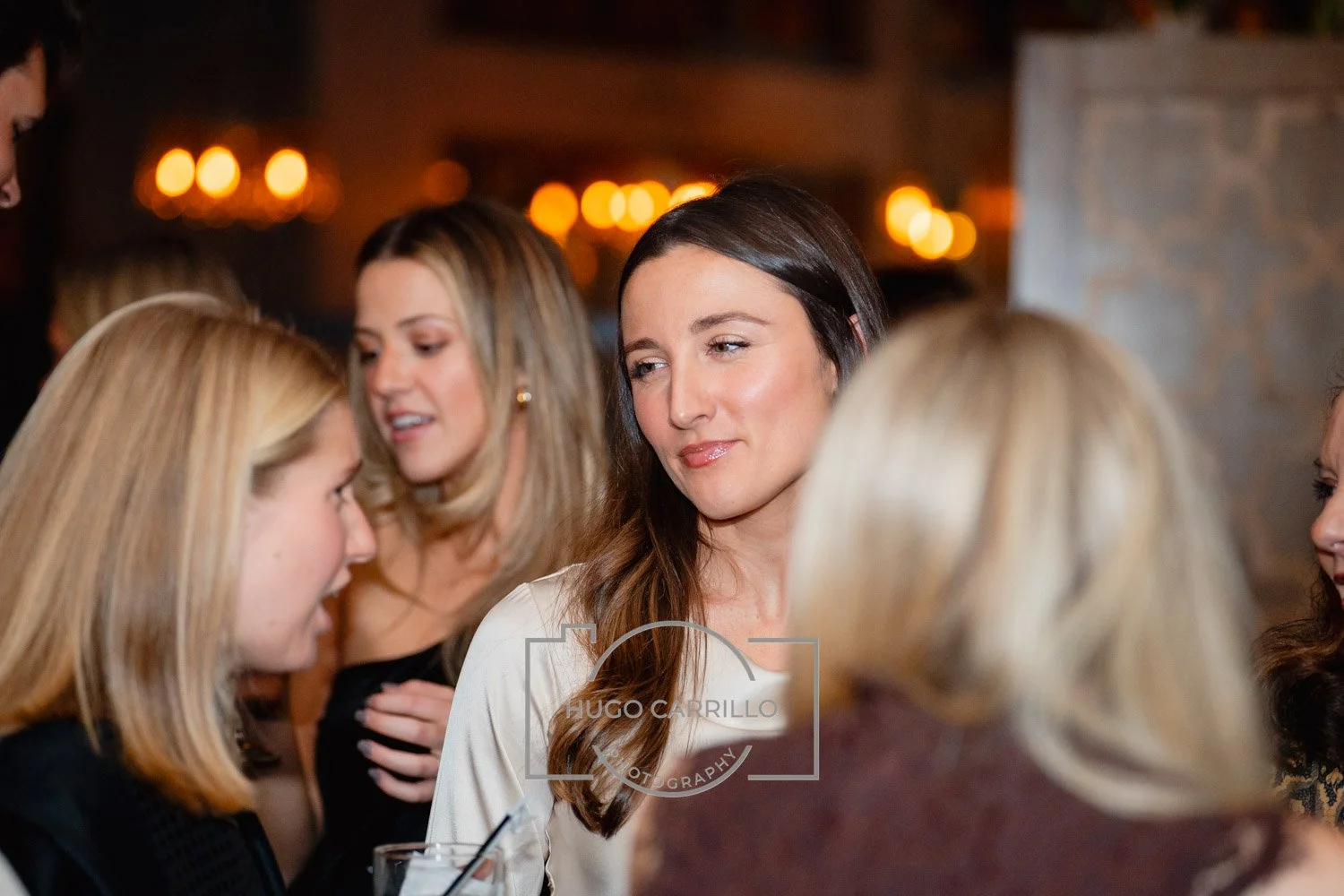 Group of women socializing at an indoor event, with warm lighting in the background.