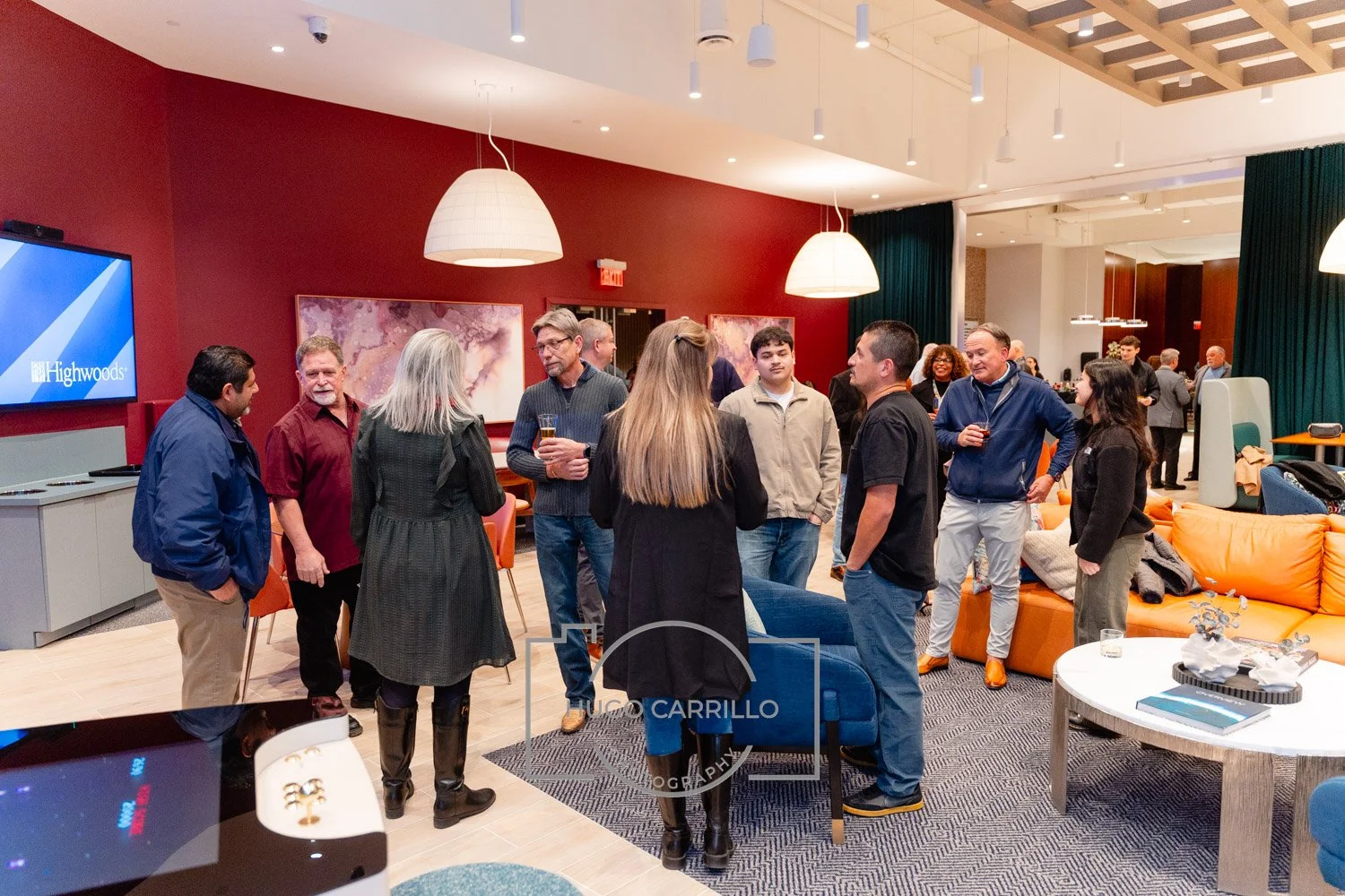 People socializing in a modern, well-lit lounge area with colorful furniture and artwork on the walls.