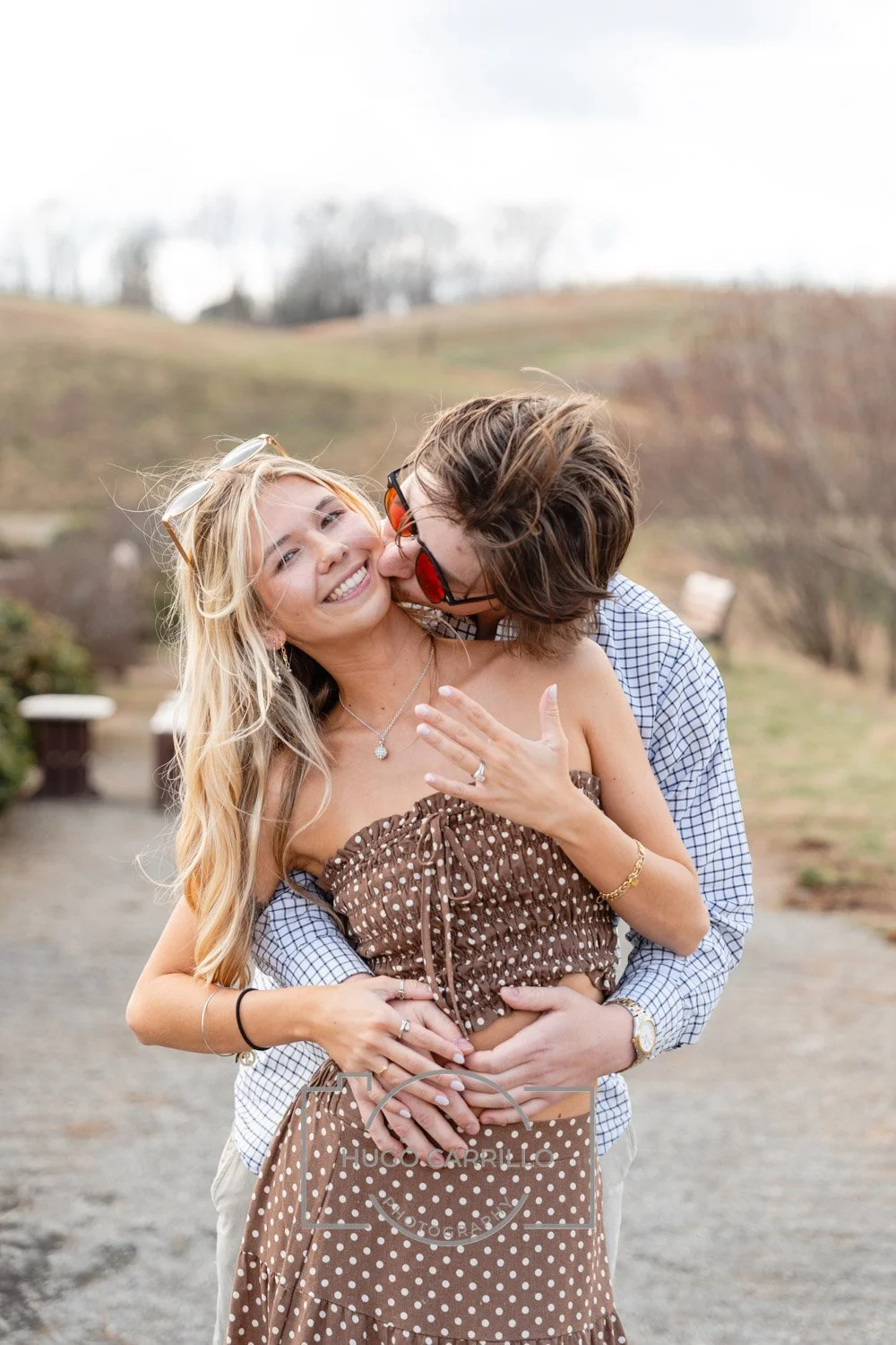A happy couple sharing an intimate moment outdoors with a scenic landscape in the background.