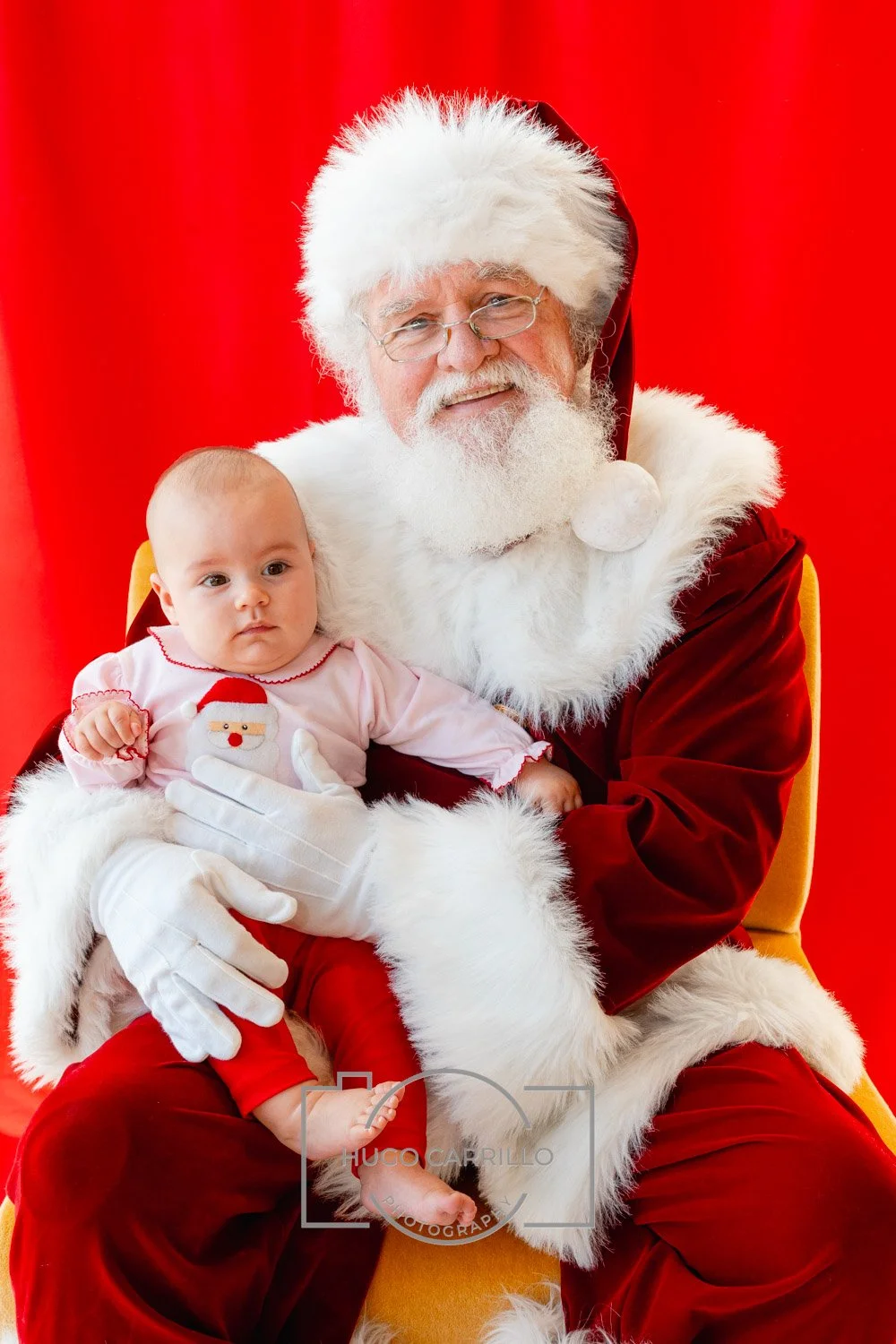 Santa Claus holding a young girl with a red background.