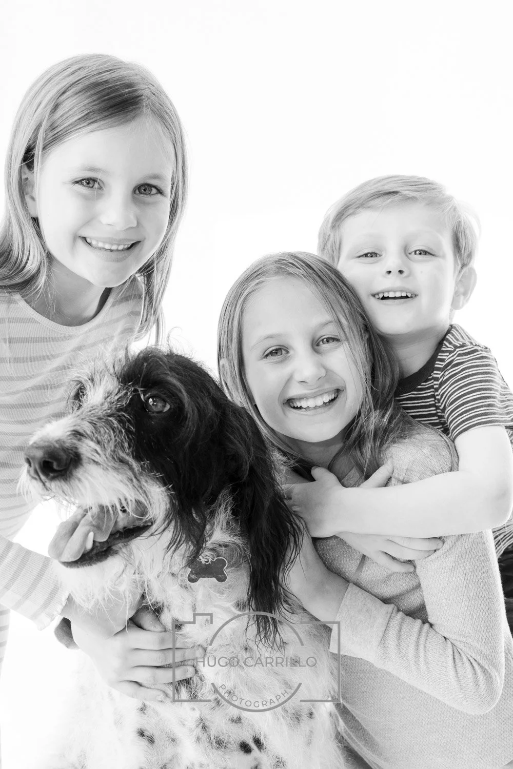 Four children and a dog smiling and hugging, black and white photo