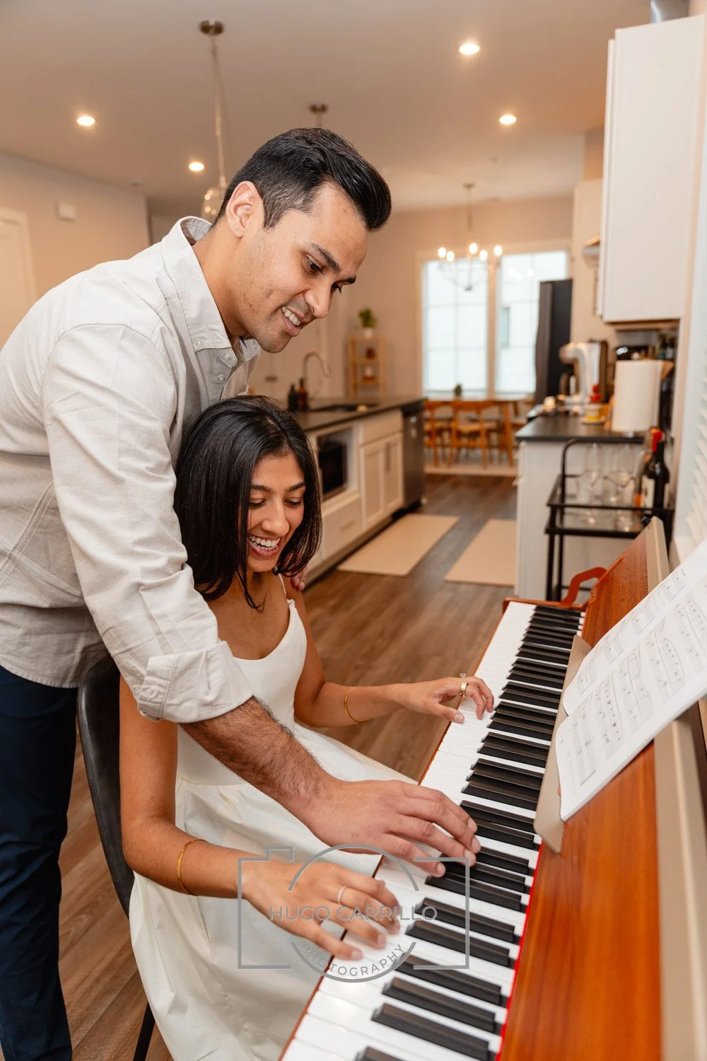 A man and woman sharing a joyful moment playing piano together in a brightly lit kitchen.