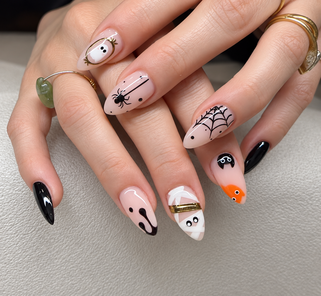 Playful Halloween nails with ghosts, spiders, spiderwebs, and mummy designs on nude pink bases. Custom nail art in Greenpoint.