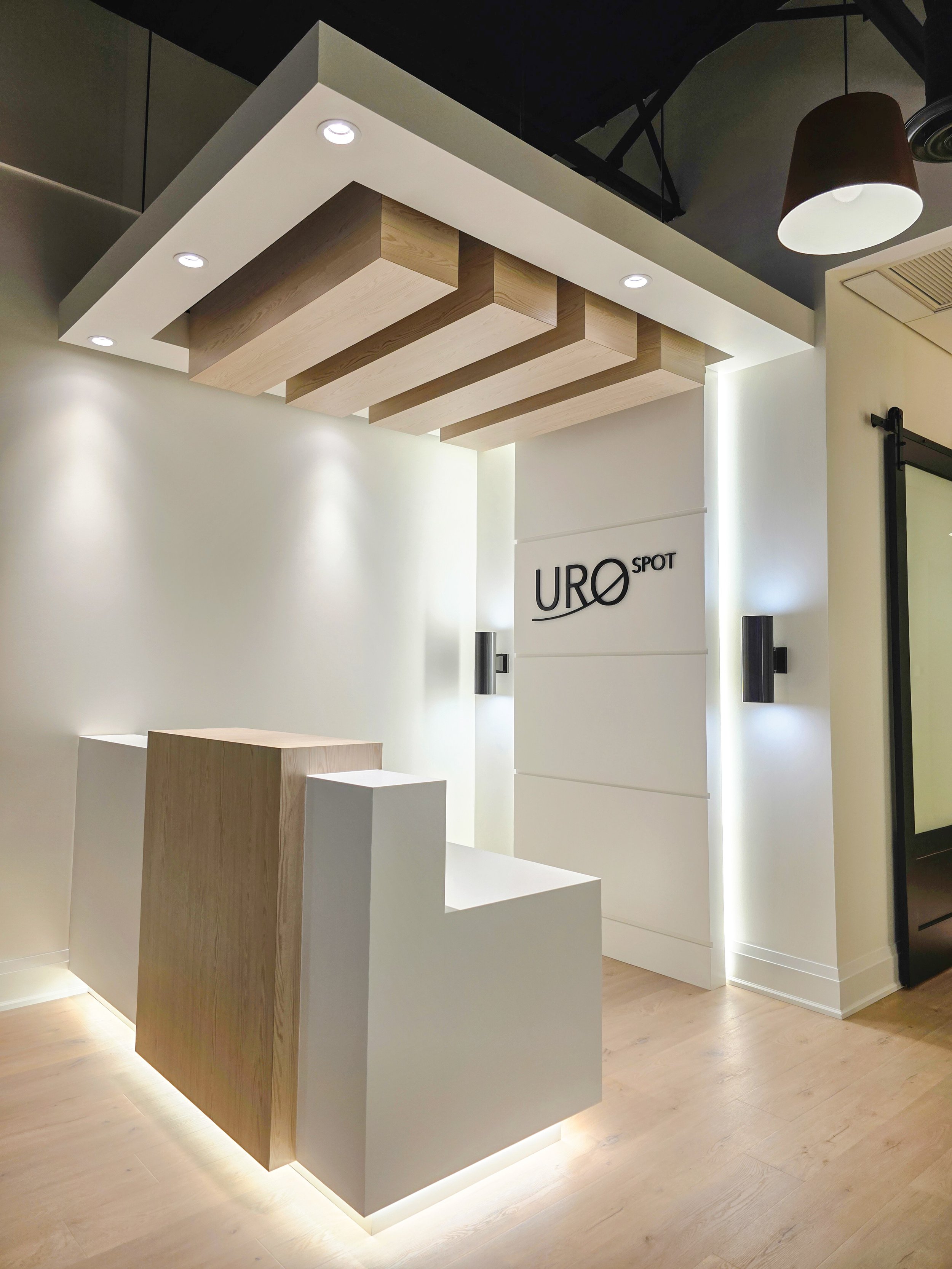 Completed a commercial tenant improvement in Orchard Plaza, Kelowna BC with interior space with modern lighting, wooden and white display structures, and the sign 'URO SPOT' on the wall.