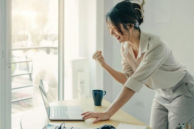 Woman celebrating a win at her computer