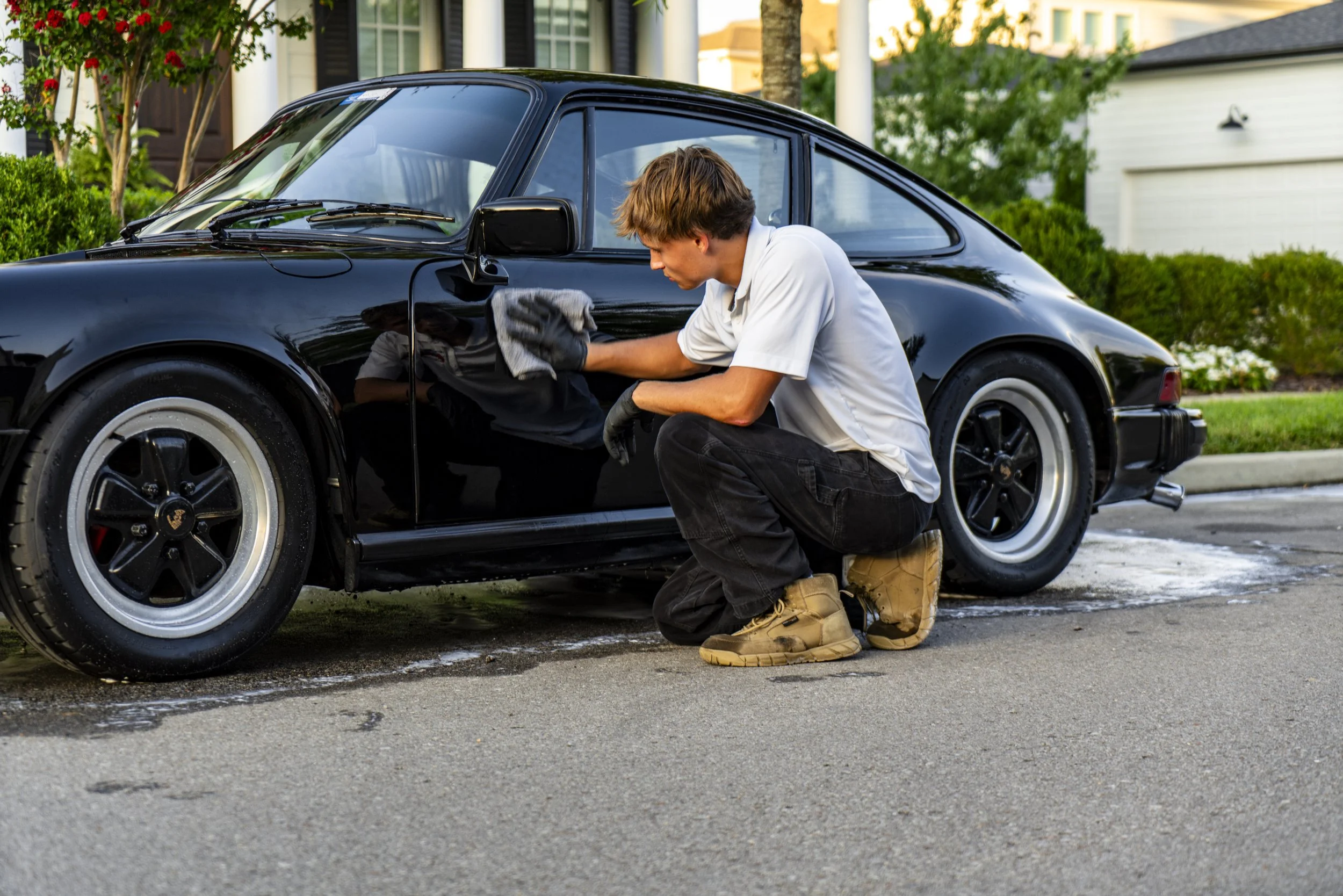 Reflections Perfection technician wiping black car’s exterior in autumn — showcasing premium hand-wash service in Franklin, TN.
