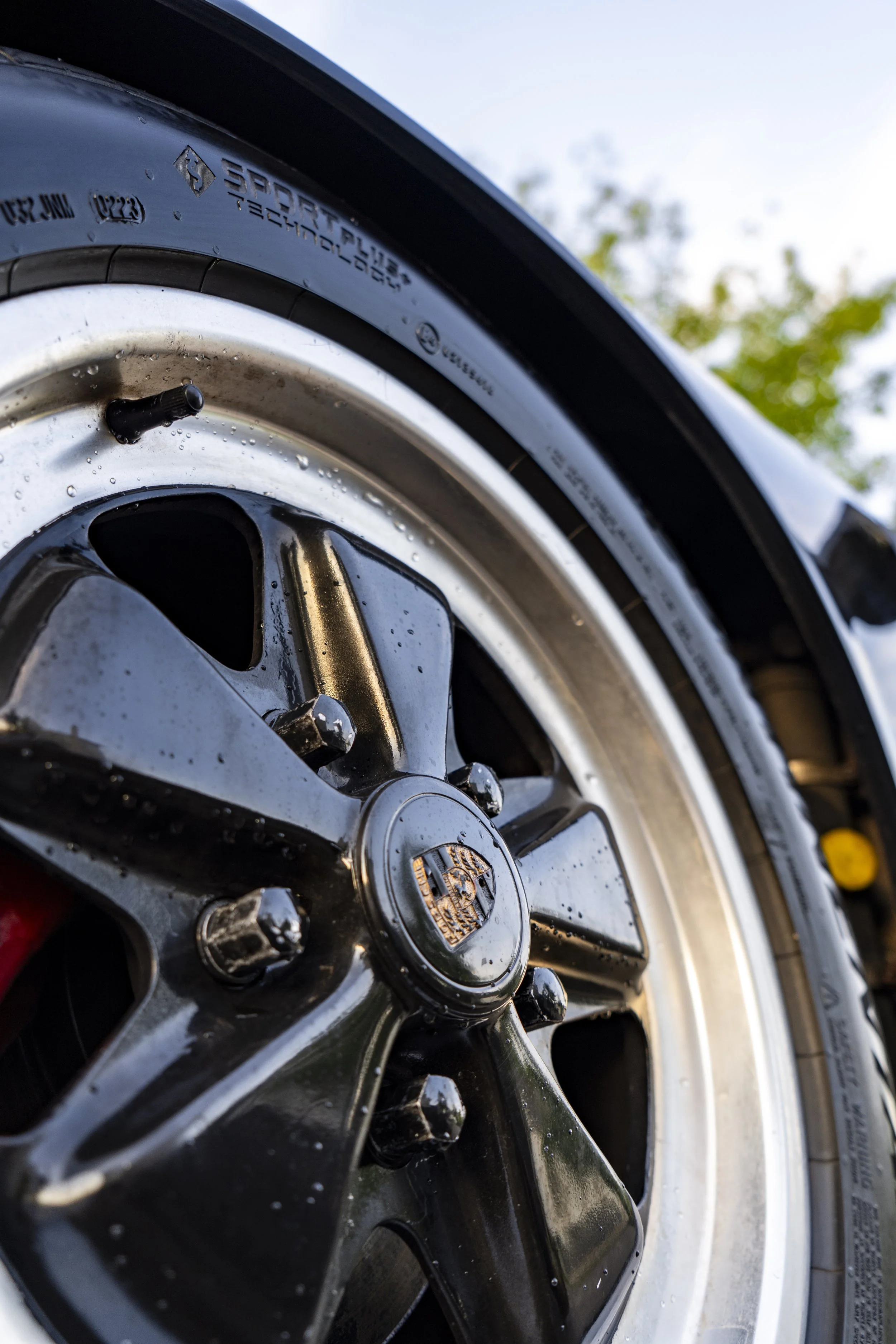 Wet Porsche brake wheel with water beads — after-care from Reflections Perfection’s high-gloss ceramic detail.
